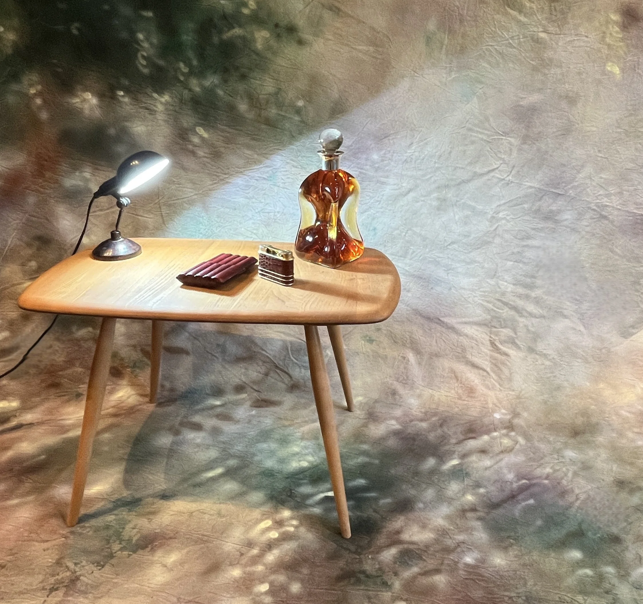 A wooden table with a decorative glass perfume bottle, a small bottle of perfume, a stack of lipstick, and a tiny lipstick container, illuminated by adjusted lighting and set against a textured wall background.
