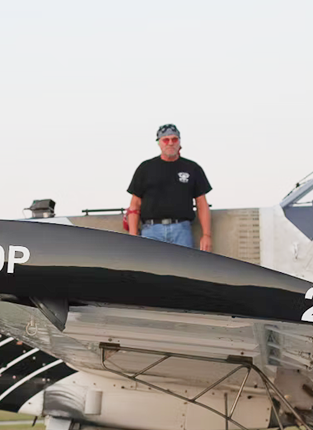 Man standing next to a black and white jet aircraft on display outdoors.