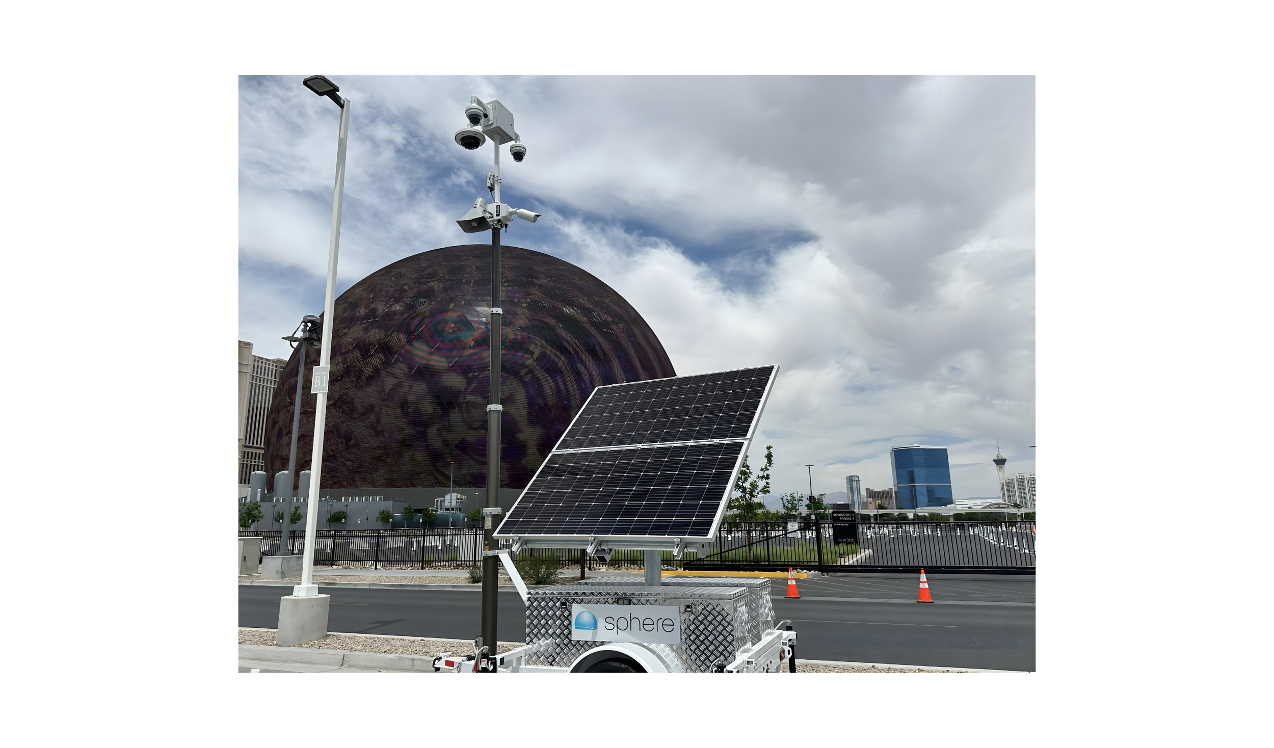 Solar panel on a trailer, with a ball-shaped satellite tracking station and security cameras in the background, along with a cloudy sky in Las Vegas
