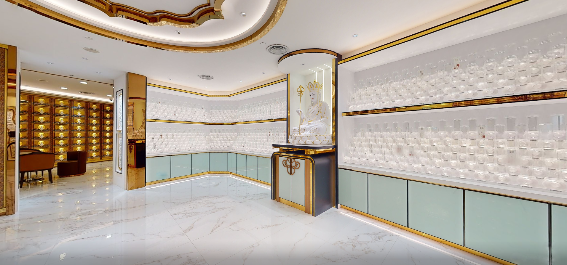 Interior of an ancestral pedestal suite with bright, elegant space with shelves of glass jars and a statue of a deity on a pedestal, featuring gold and white accents, marble flooring, and a seating area with chairs and a table.