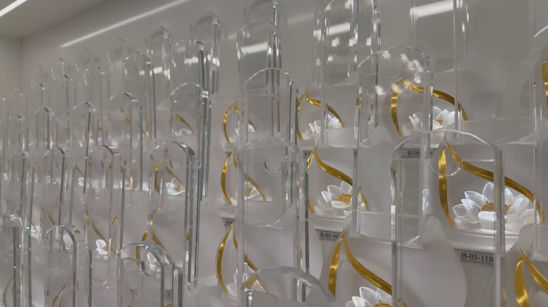 A display of crystal and gold decorative ancestral pedestals arranged on clear acrylic stands in a store or display case.