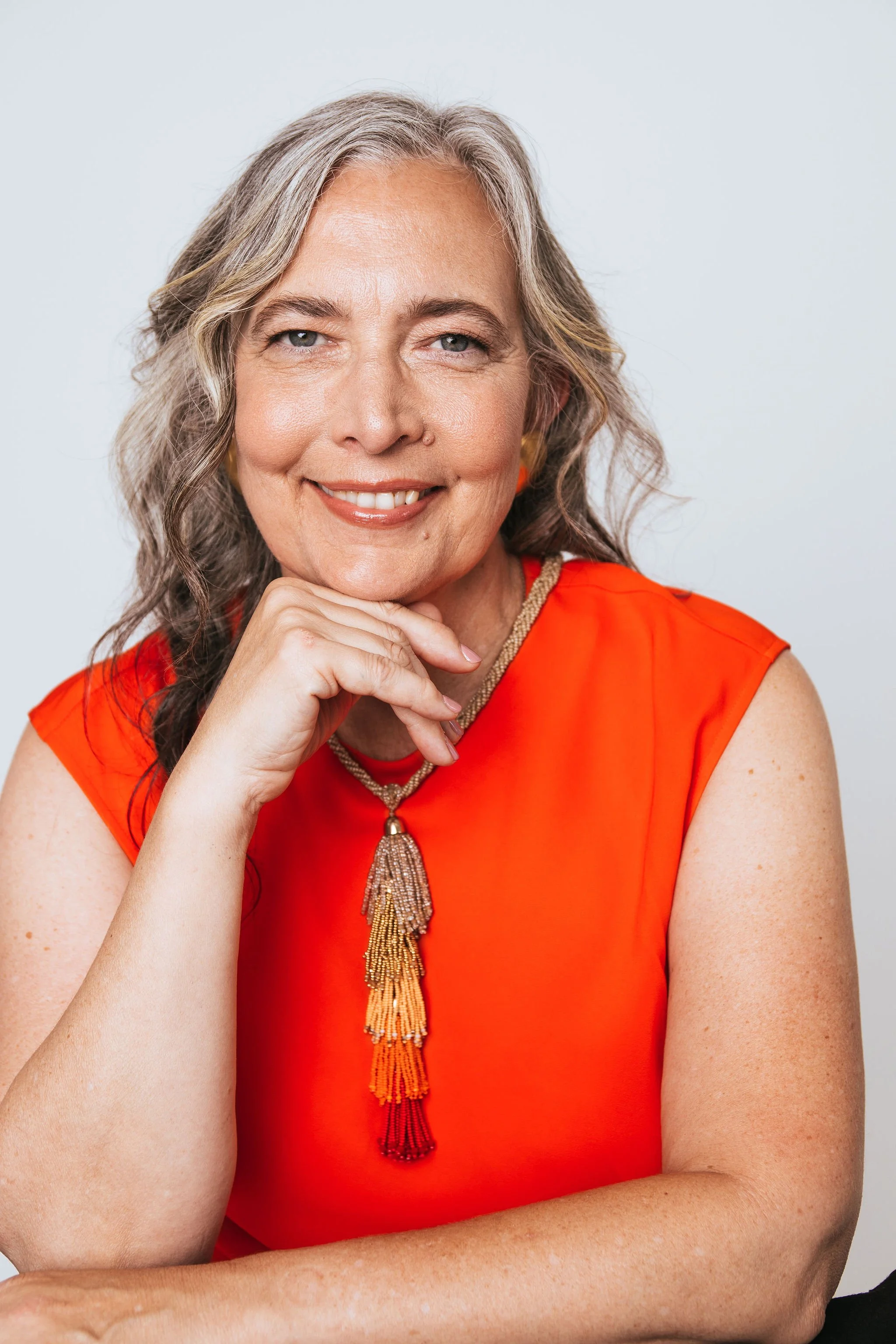 Head shot of Dr. Jennifer Dall in orange sleeveless top with beaded necklace