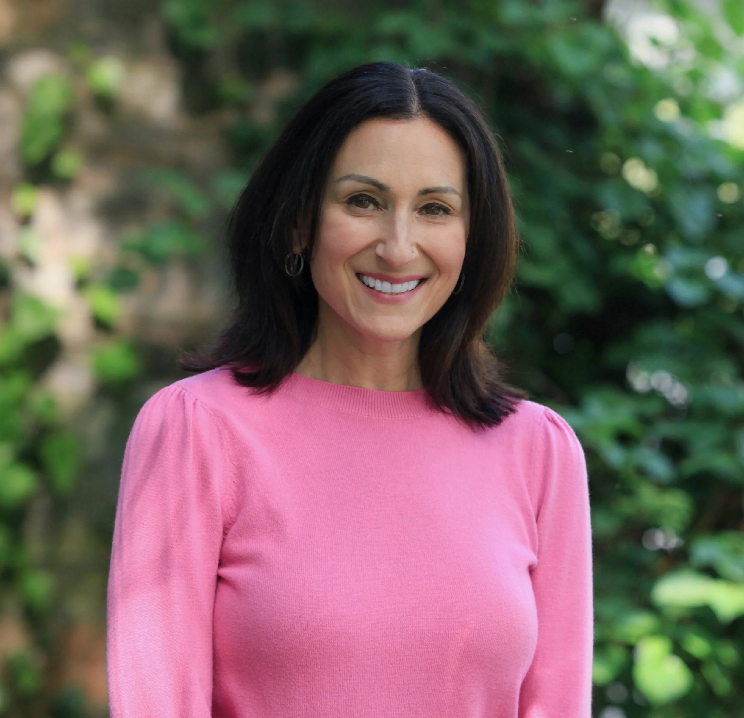 Brooke Bralove, sex therapist, wearing pink sweater smiling at camera