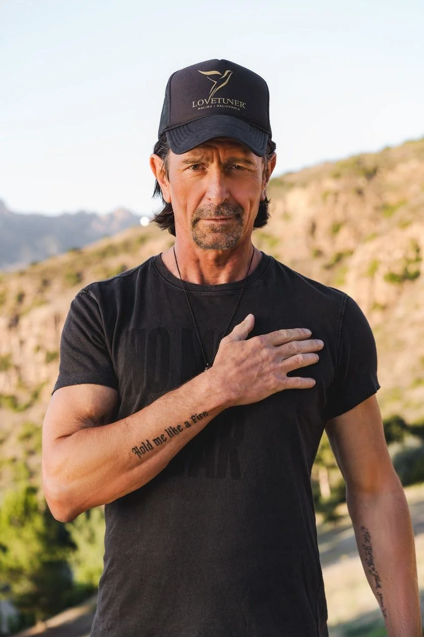 Sigmar Berg in black T-shirt and black hat with right hand over his heart