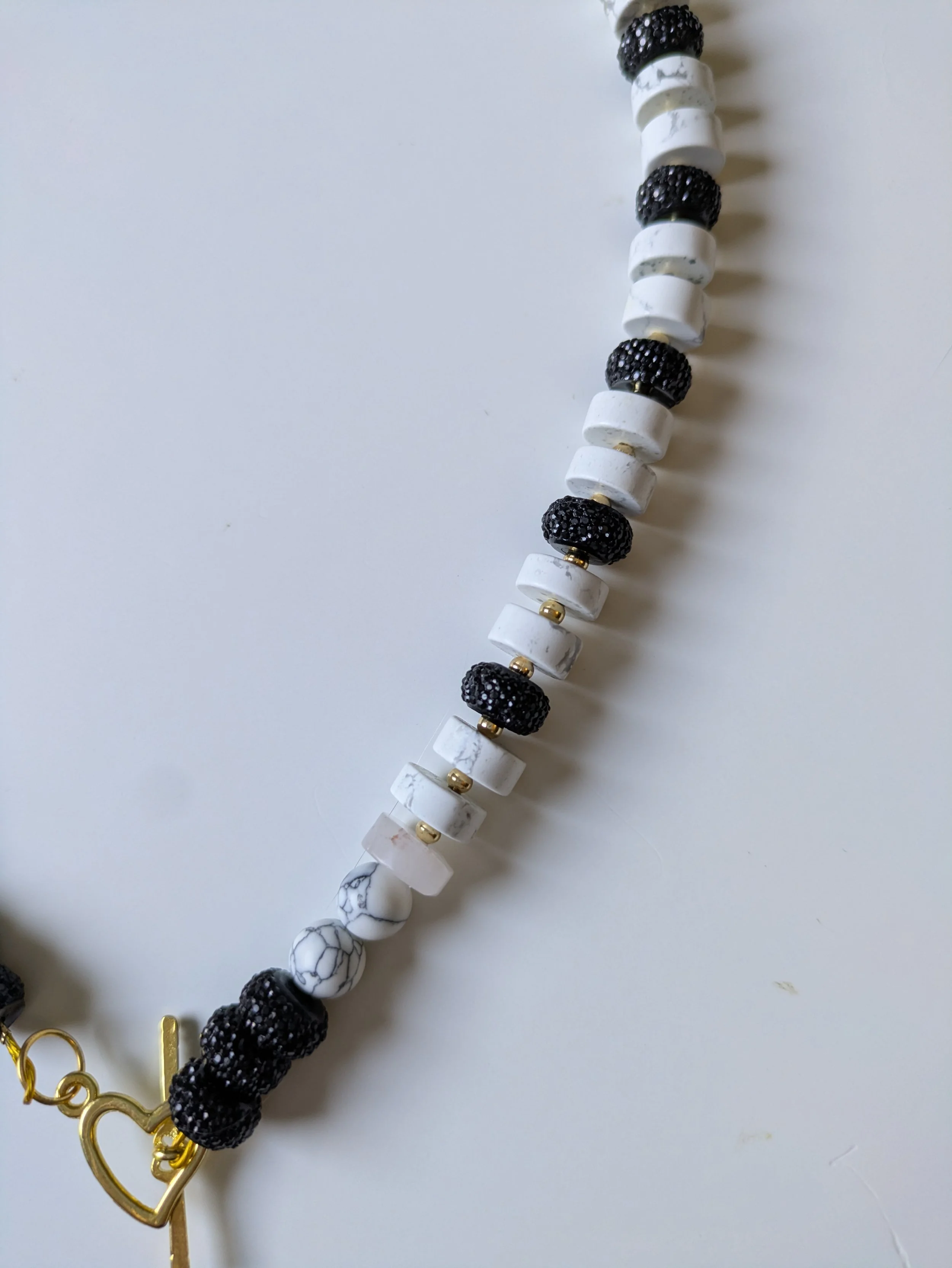 Half of a black and white beaded necklace with gold details.