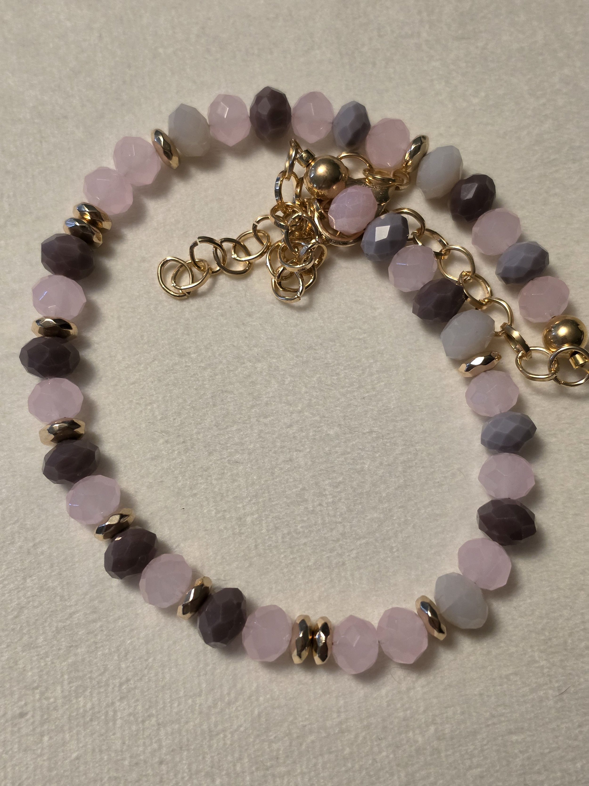A purple and pink glass beaded necklace with gold accents