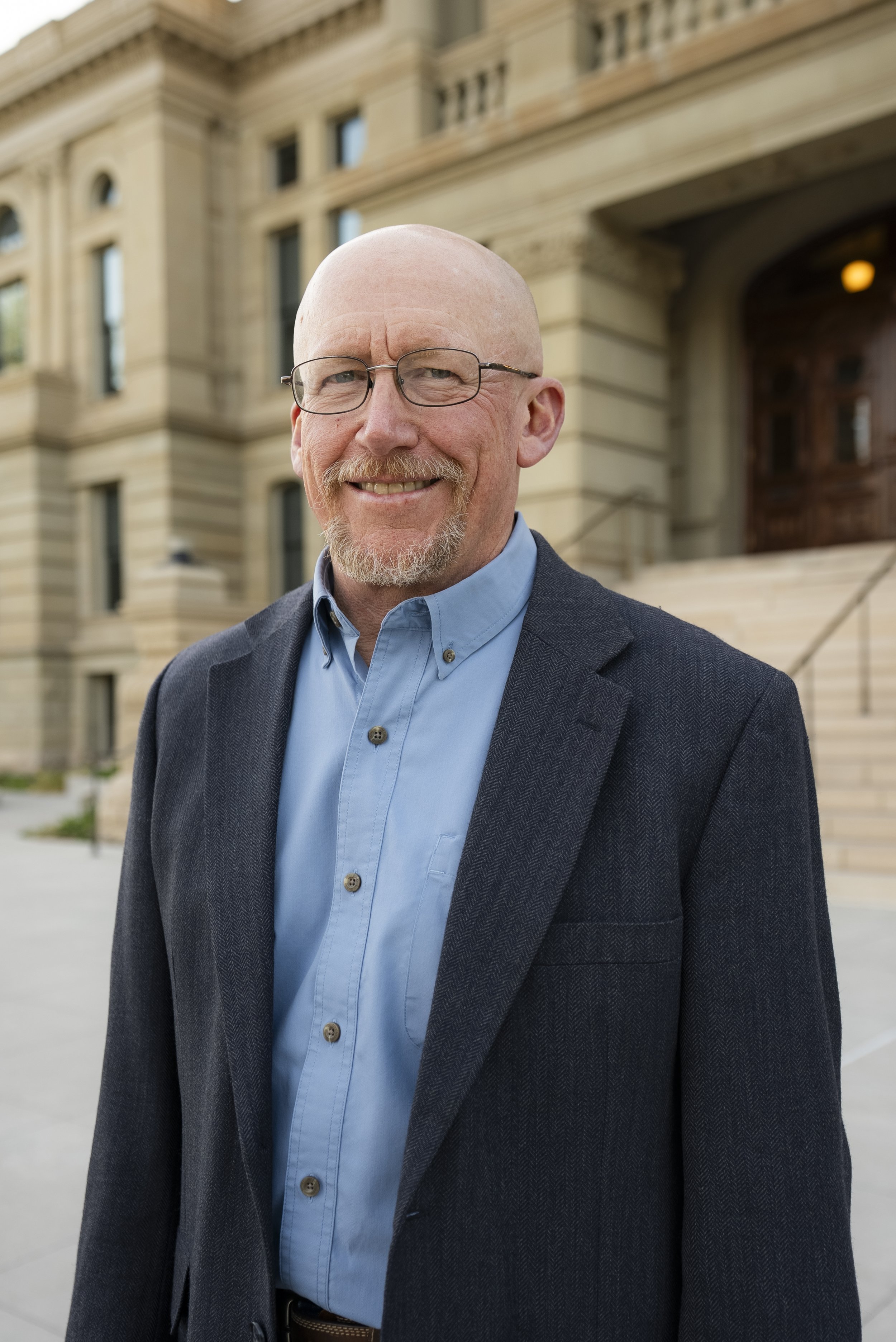 Portrait of Luke Reiner, Candidate for Wyoming House District 8, smiling in front of the Wyoming State Capitol Building