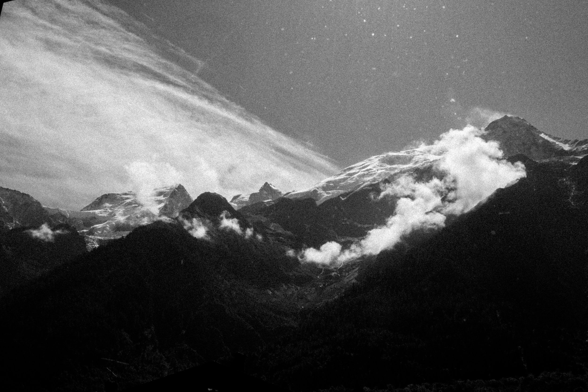 Montagnes enneigées avec des nuages et un ciel étoilé - Chamonix Mont-Blanc -  Alps Films Equipment Rental.