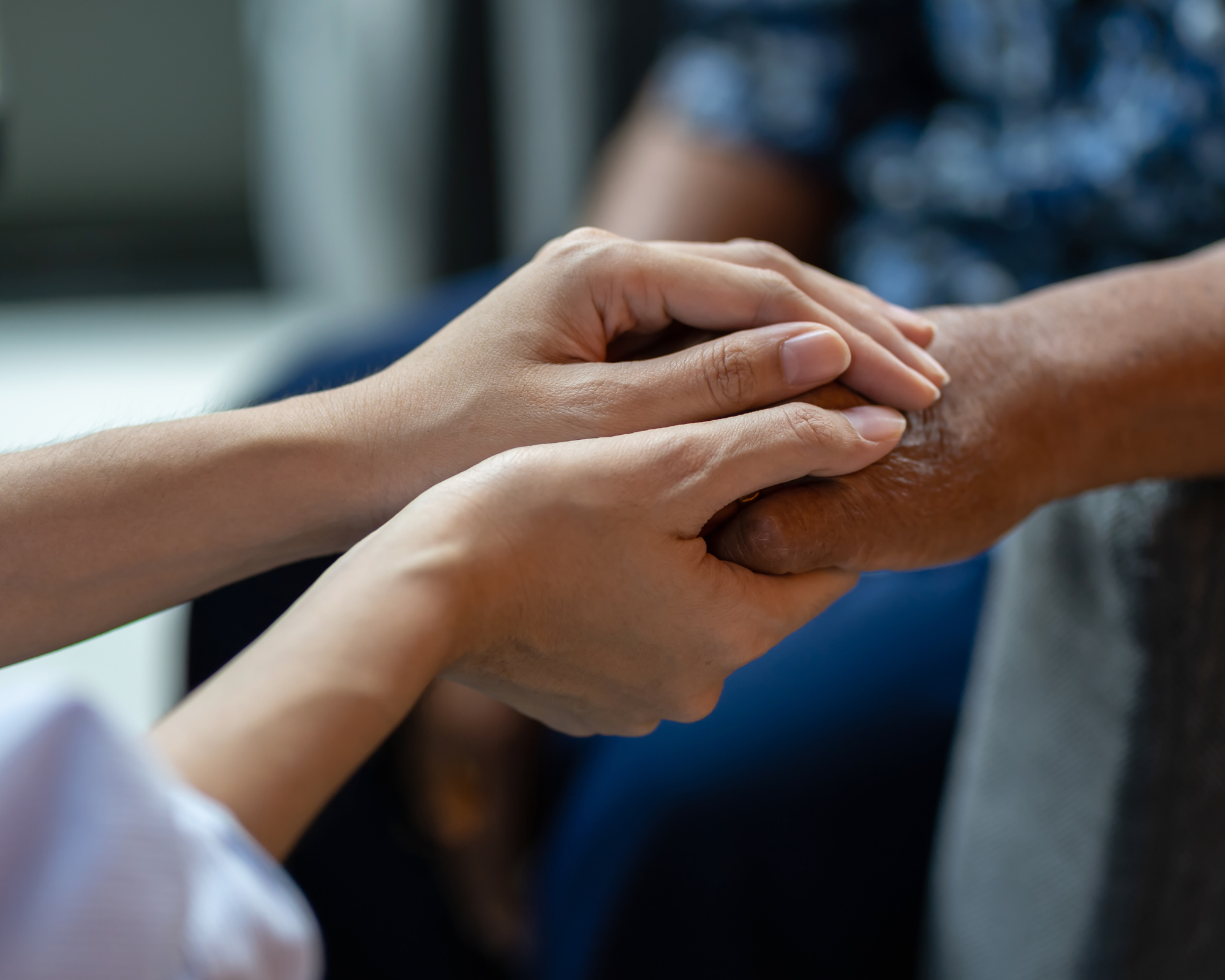 Close-up of a person's hand resting on top of another person's hand, suggesting a comforting or affectionate gesture.