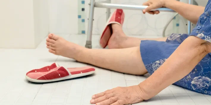 Person exercising on the floor in a medical setting, with red shoes and a walker visible.