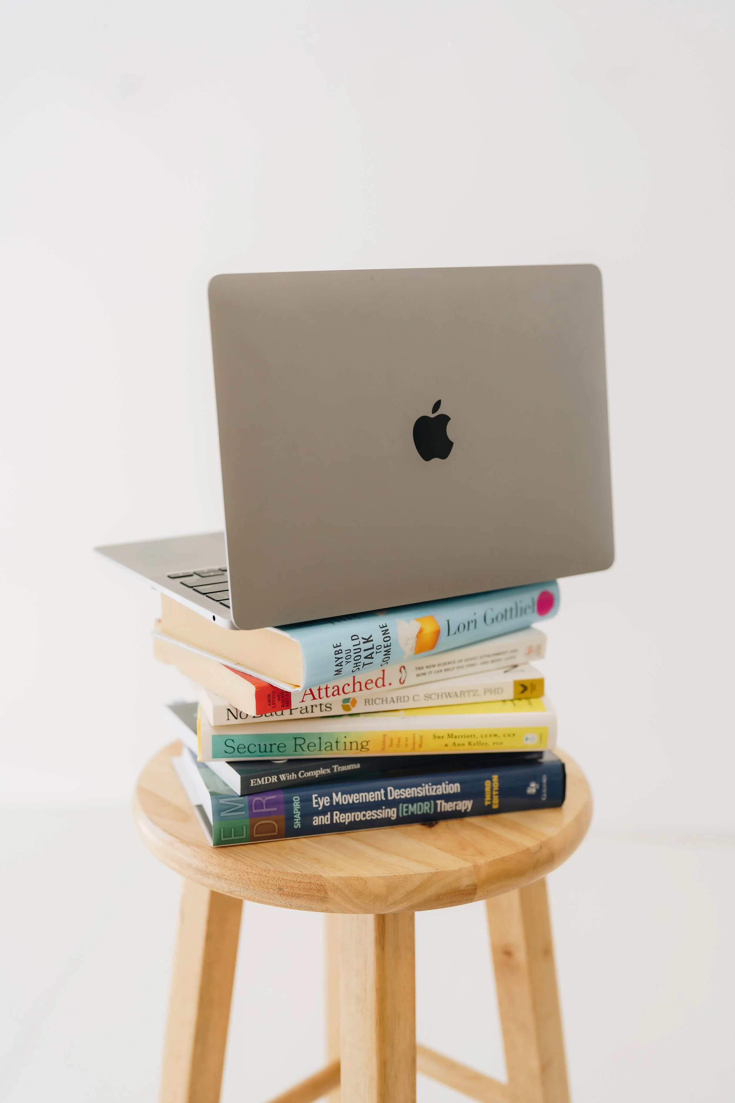 laptop on psychology books about attachment, emdr, and relationships
