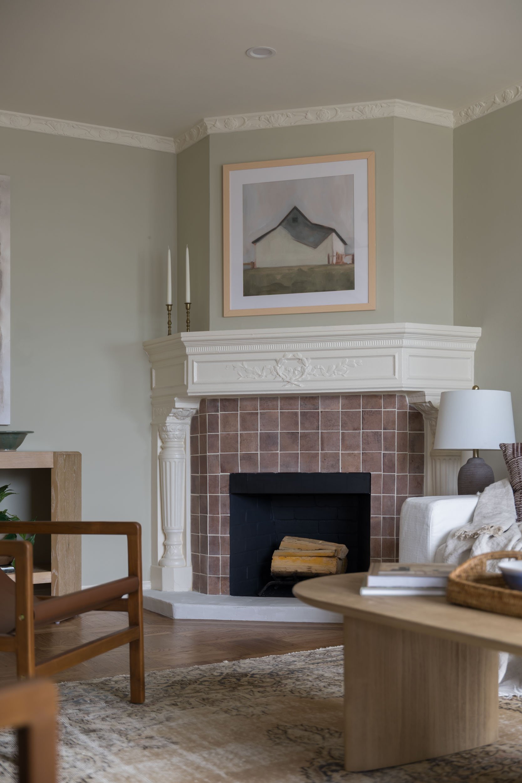 Living room with a fireplace, painting above, and wooden furniture.