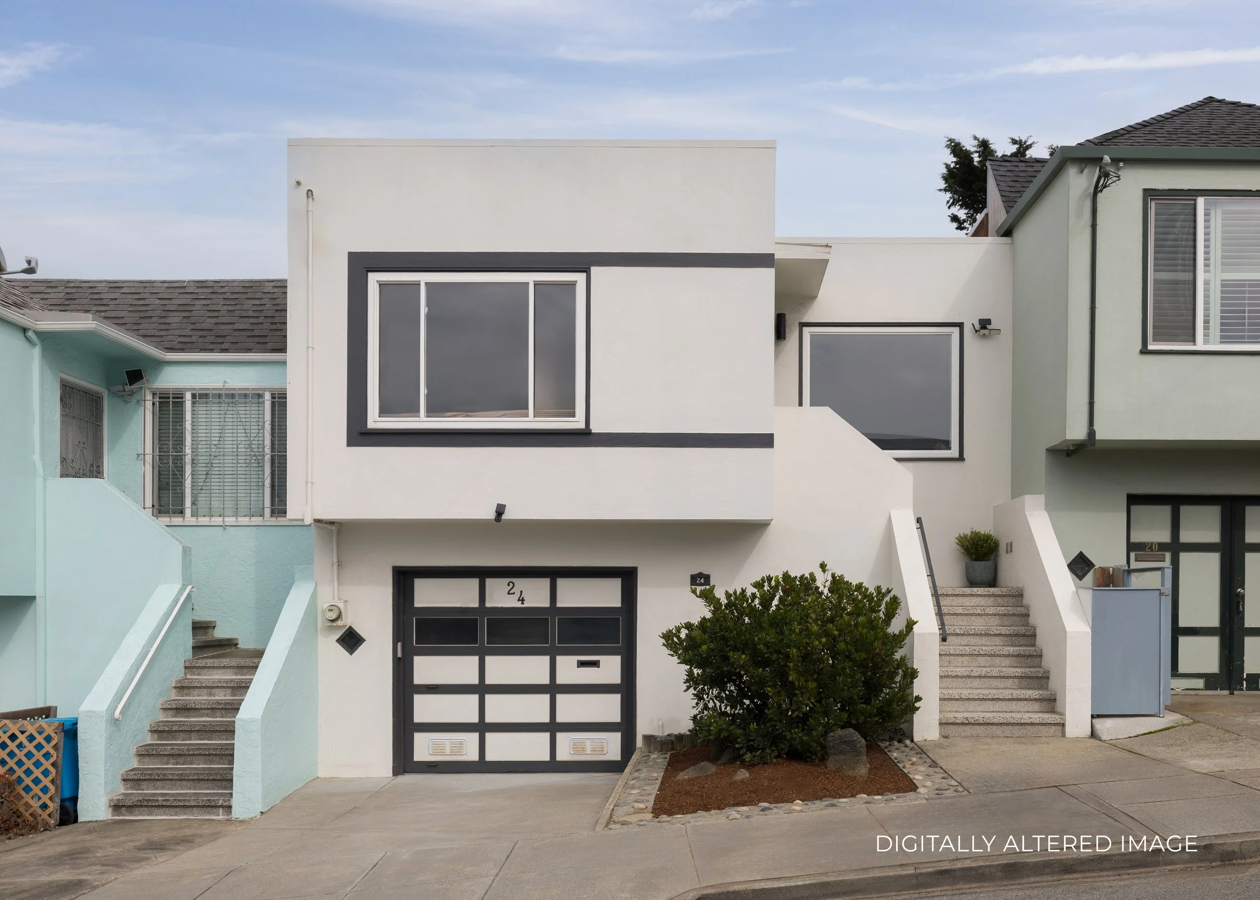 Front view of a modern, white two-story house with black trim, adjacent to two other houses, with stairs leading up to entrances and a small landscaped area with a bush in front.
