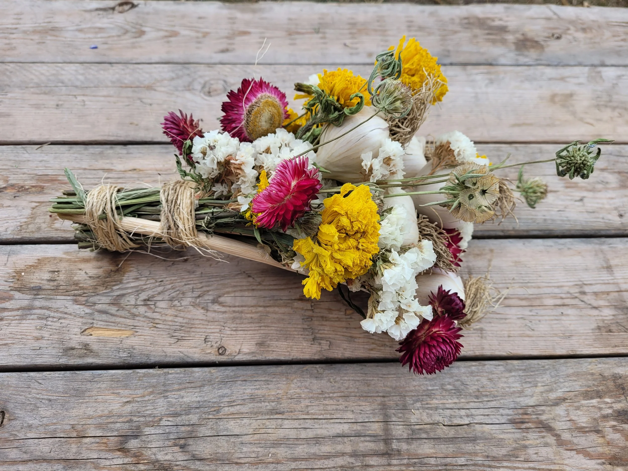 A dried flower bouquet with yellow, white, and pink flowers