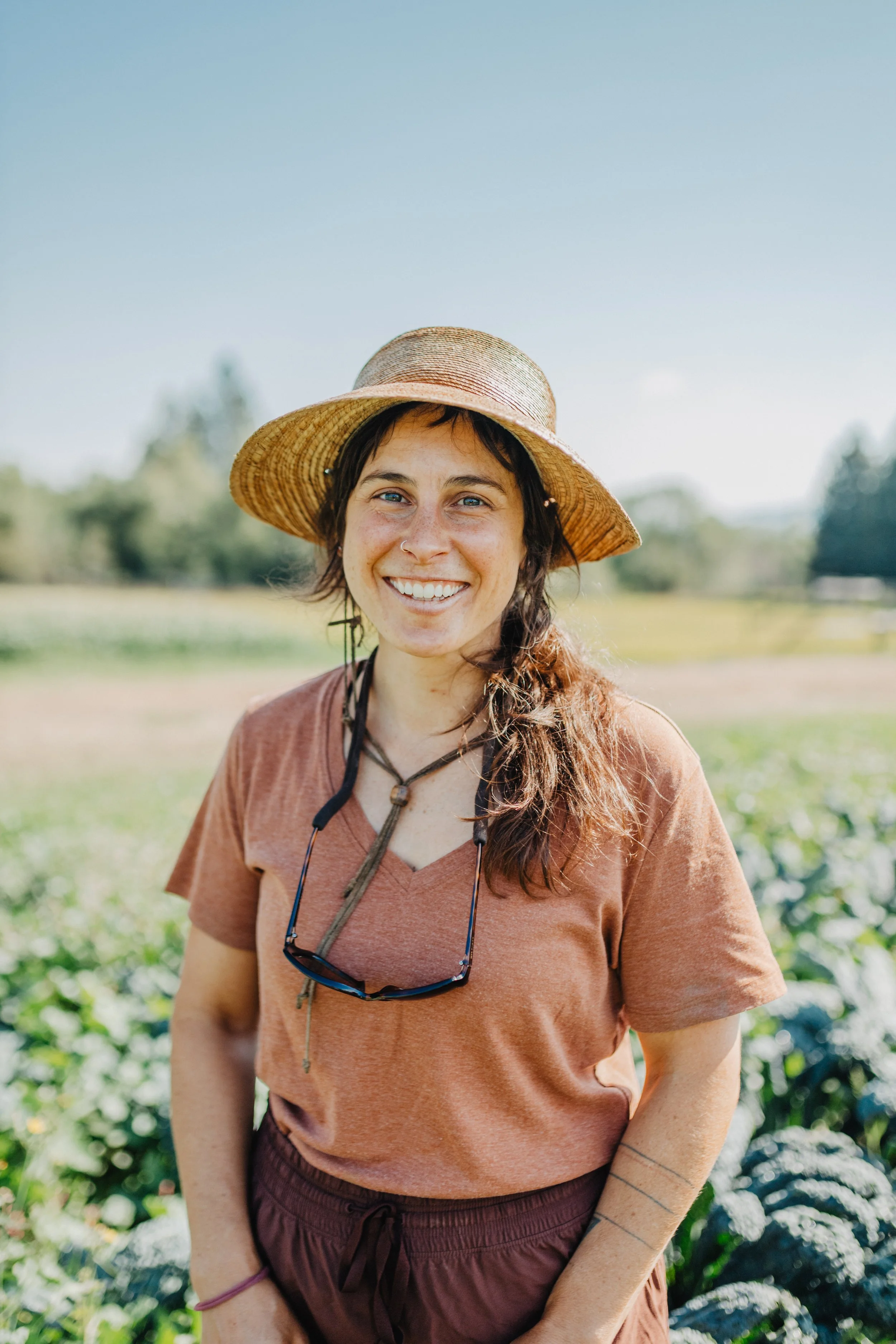 Ellie Costello, owner of Trust Land Farm, smiling on the farm wearing a sunhat