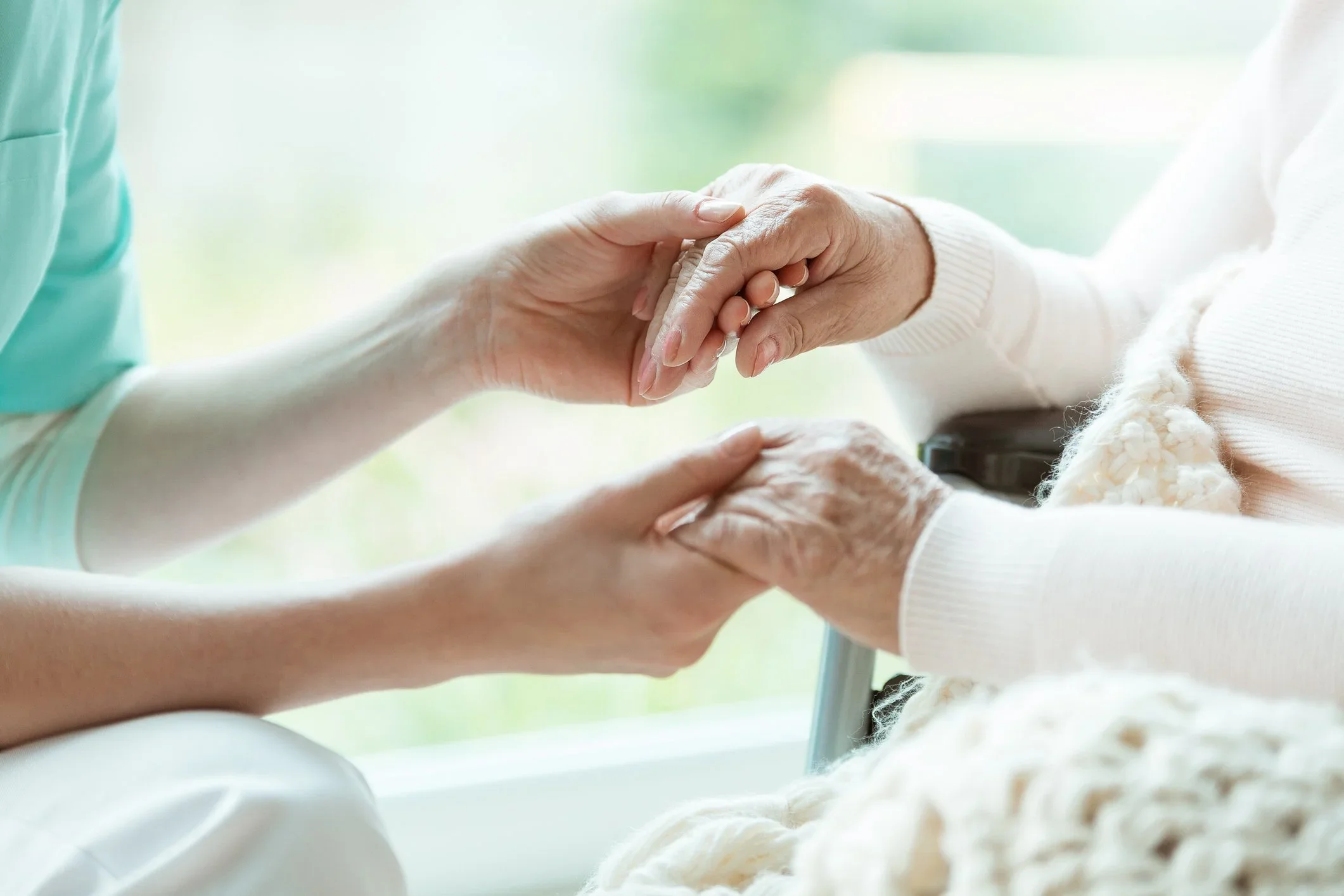 Personal Care - Home Care - Specialized Care - Disability Care - Post Hospital Care - Memory care - Dementia care - Companion  Care - Close-up of two hands holding each other, one appears older and the other younger Rosebuds' caregiver.