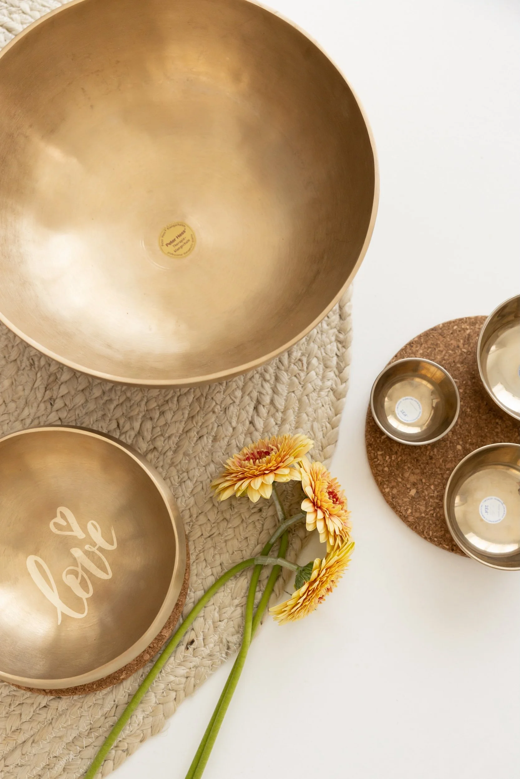 Kuvassa on useita kultaisia äänimaljoja ja kaksi pienempää aseteltuna pöydälle äänimaljarentoutusta varten.