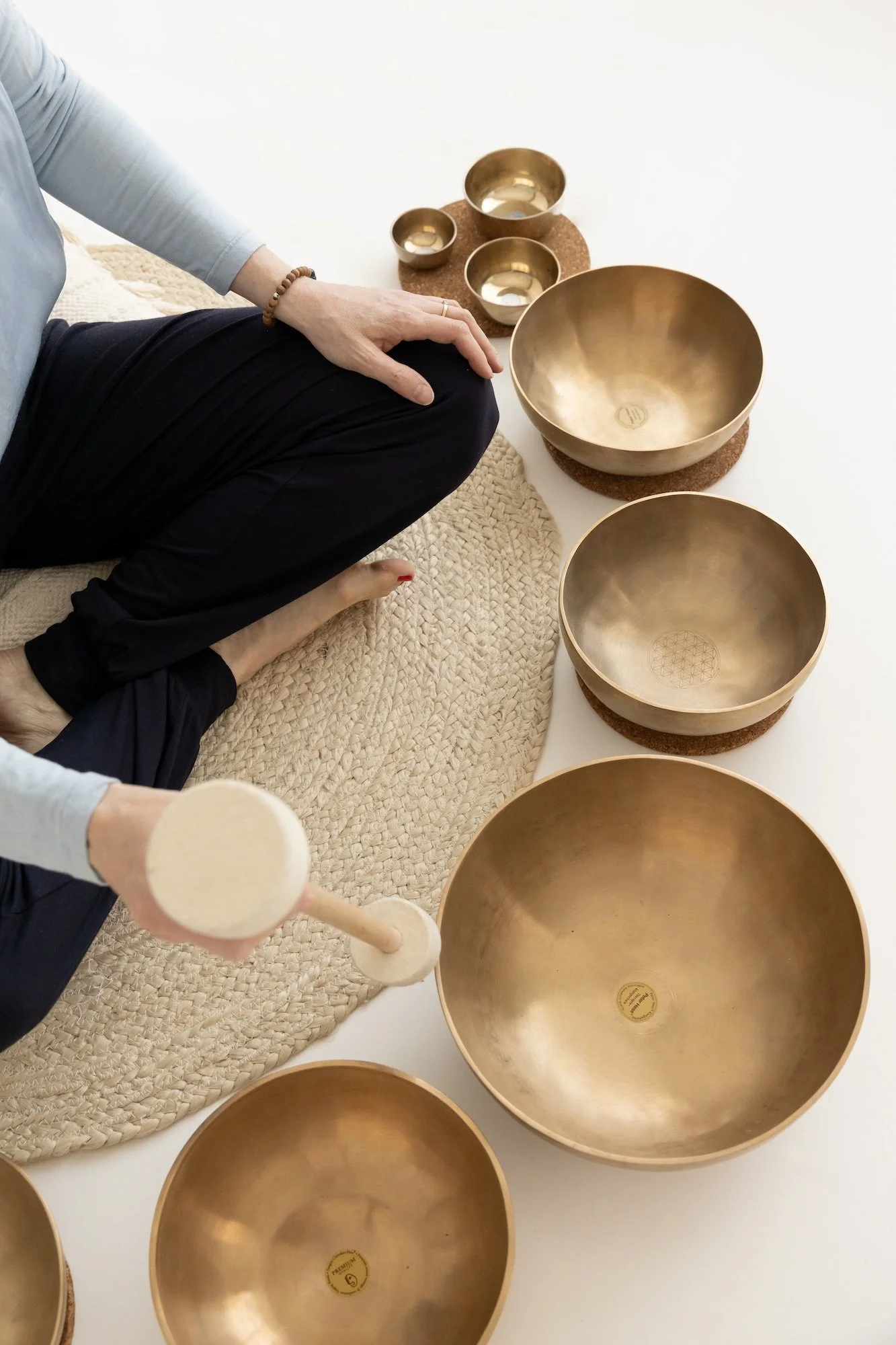 Kuvassa on useita kultaisia äänimaljoja ja kaksi pienempää aseteltuna pöydälle äänimaljarentoutusta varten.
