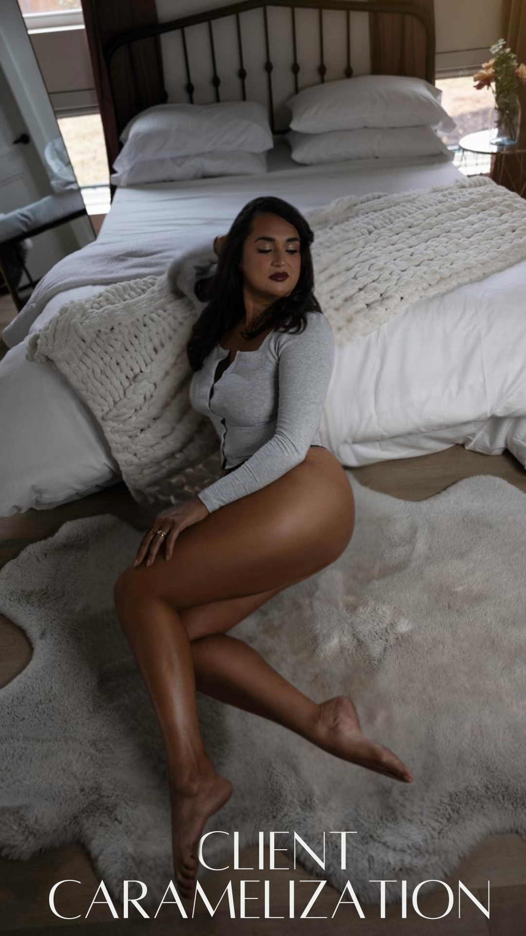 A woman with dark hair and dark lipstick sitting on a plush rug in front of a bed with white bedding and a knitted throw blanket, in a bedroom setting with a flower arrangement on a side table, with the text "Client Caramelization" at the bottom.