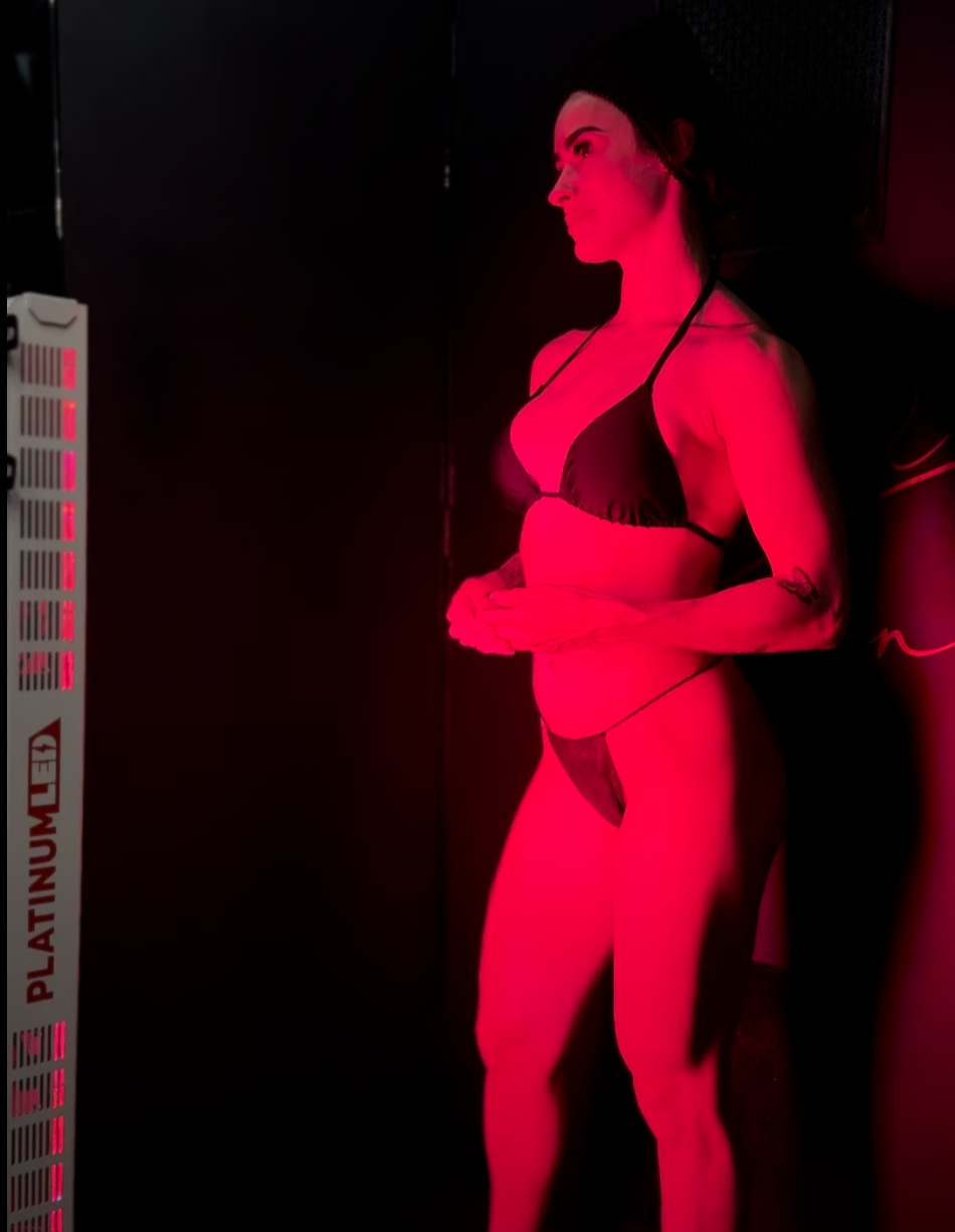 Client relaxing under red light therapy on grounding mat inside Caramel Tan Wellness Studio in Central East Austin.