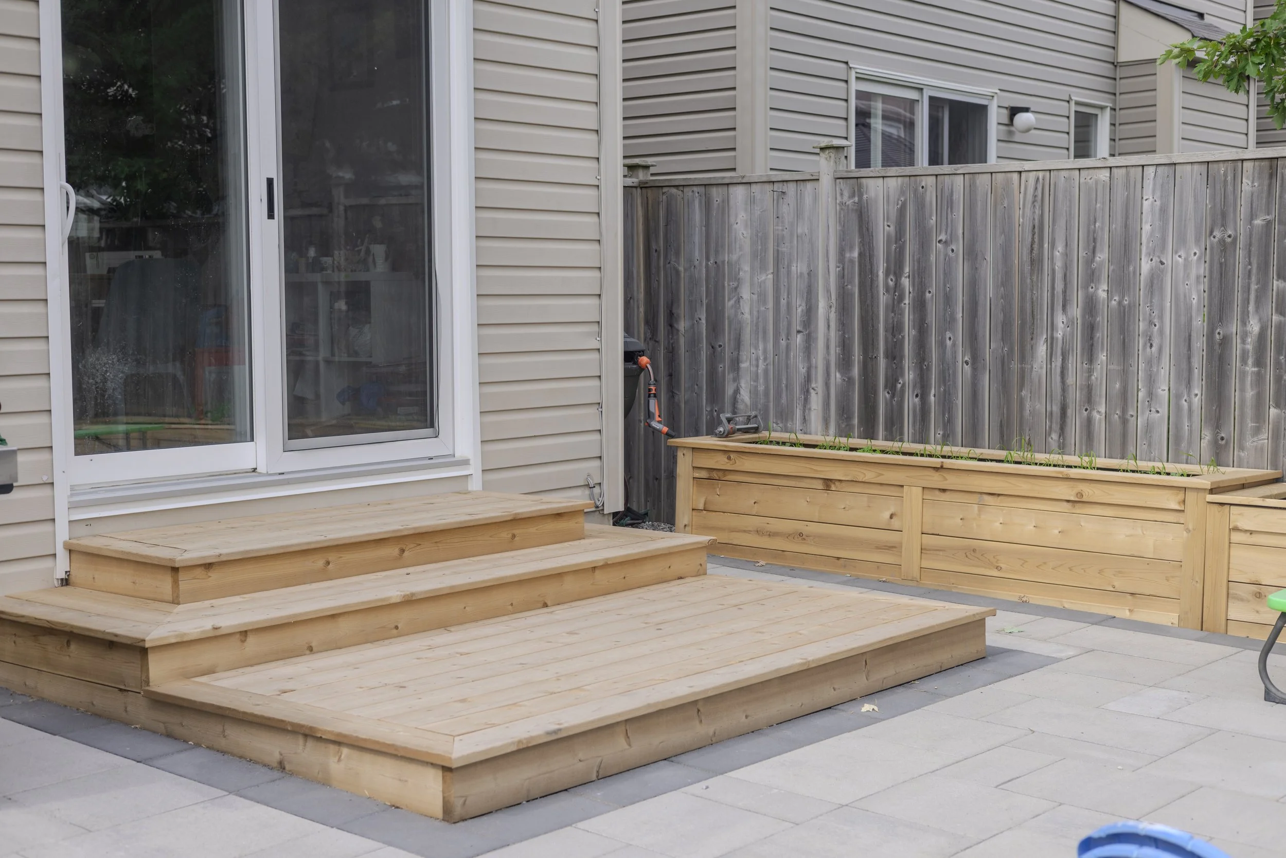 Backyard patio with wooden steps and deck transition in Ottawa