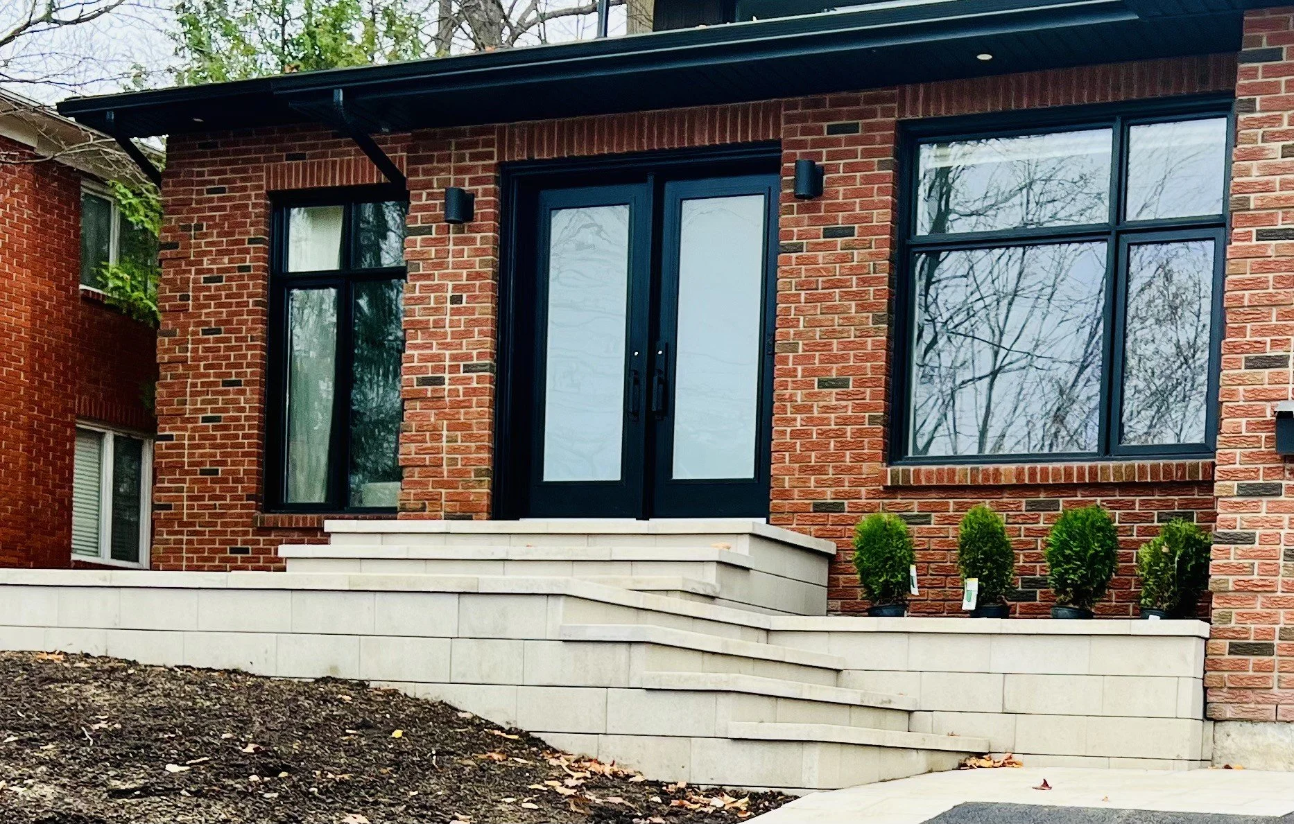 Newly built interlock front entrance with black door and stonework in Ottawa