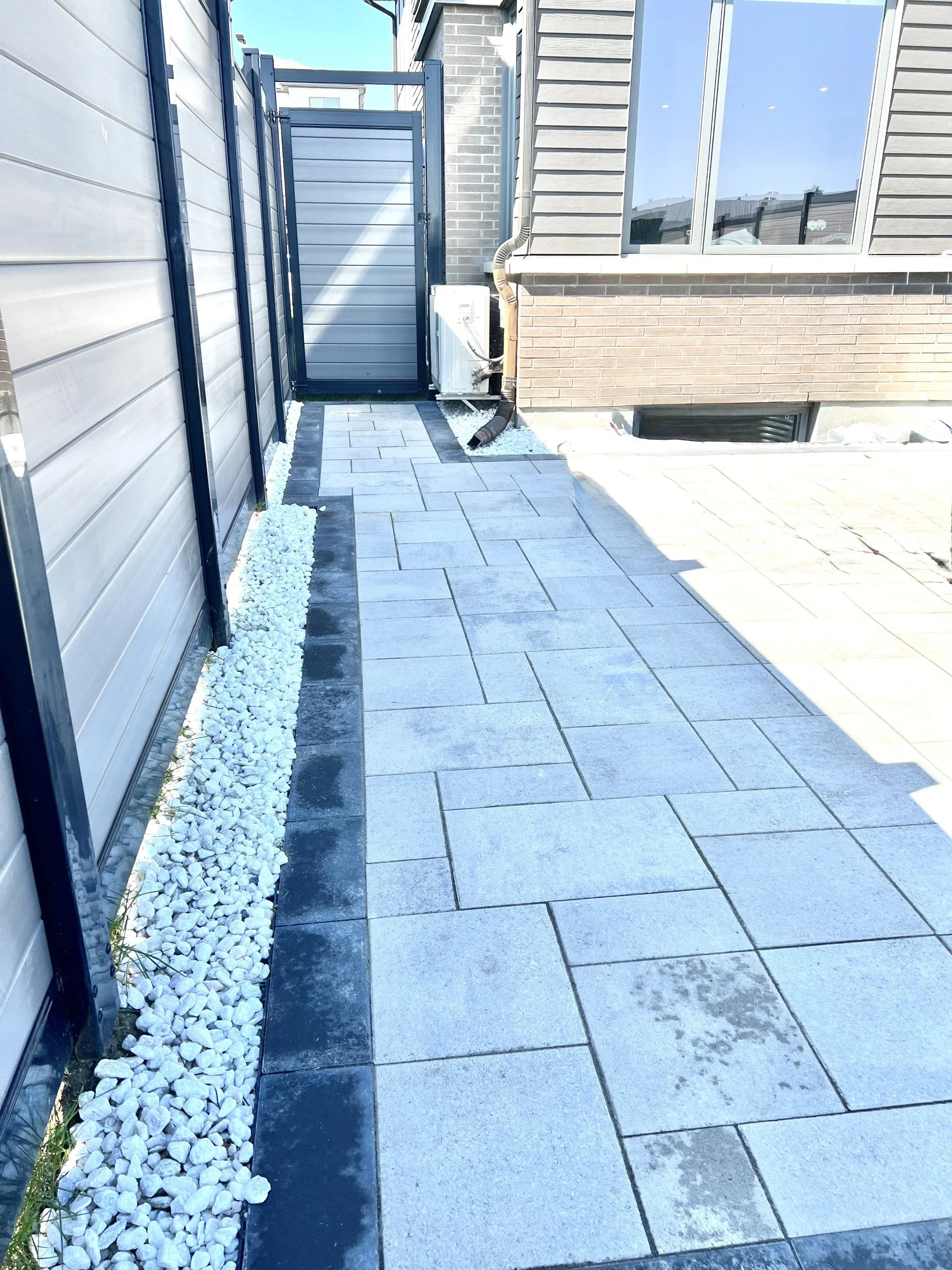 Modern backyard patio with grey interlock pavers and side yard walkway in Ottawa
