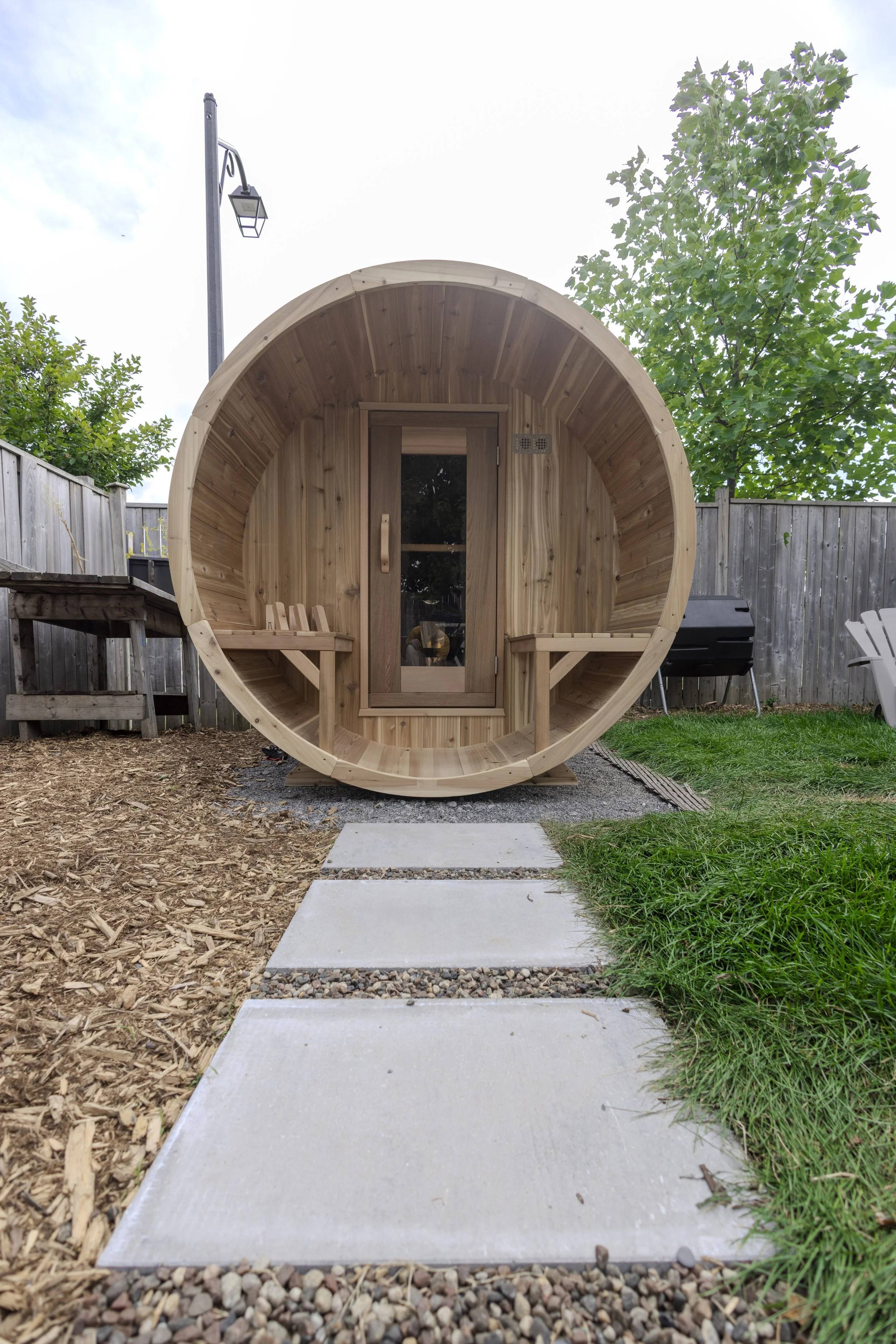 Backyard landscaping with walkway leading to outdoor sauna in Ottawa