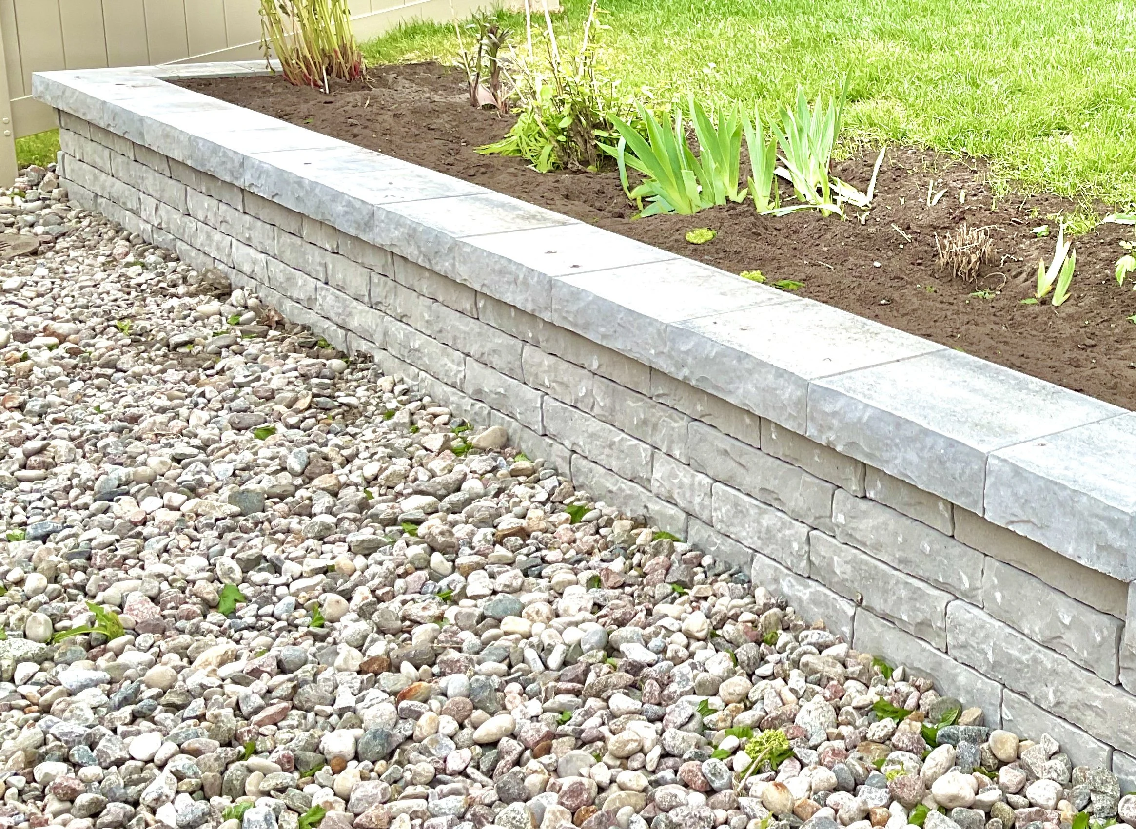 Garden bed with stone retaining wall and decorative gravel in Ottawa