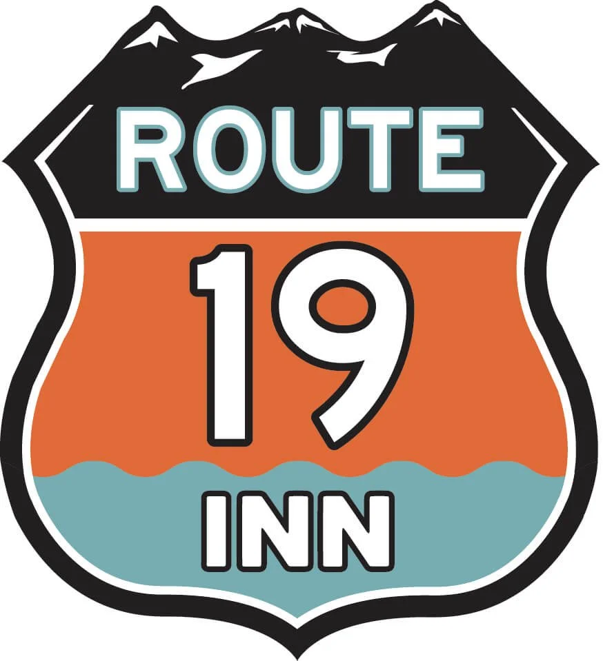 A graphic of a road sign featuring a mountain range at the top, with the word 'ROUTE' at the top, the number '19' in large font in the middle, and the word 'INN' at the bottom. The sign is divided into sections with different colors, including black, orange, and light blue.