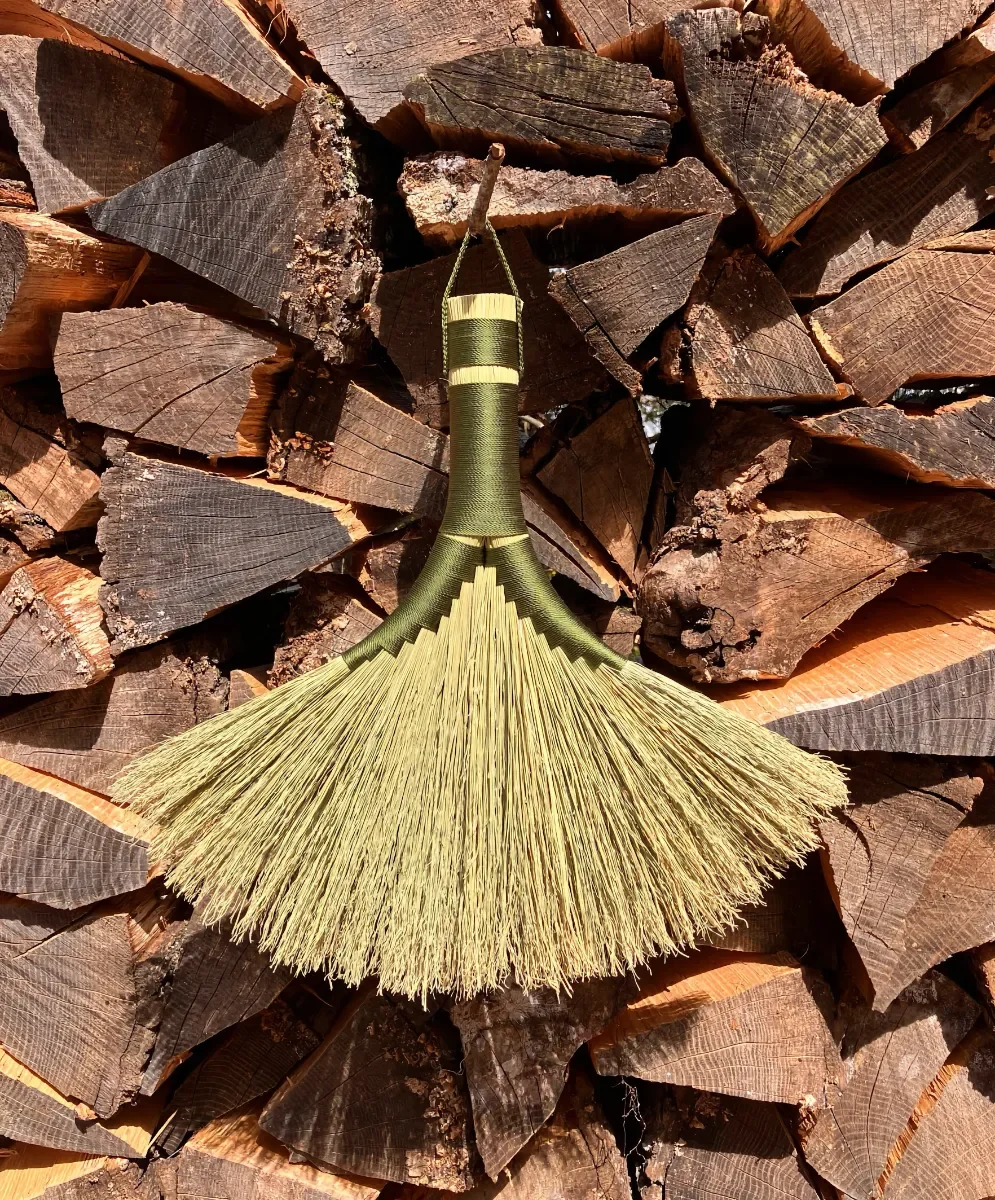 Double turkey wing broom made with green nylon screen with a wooden background
