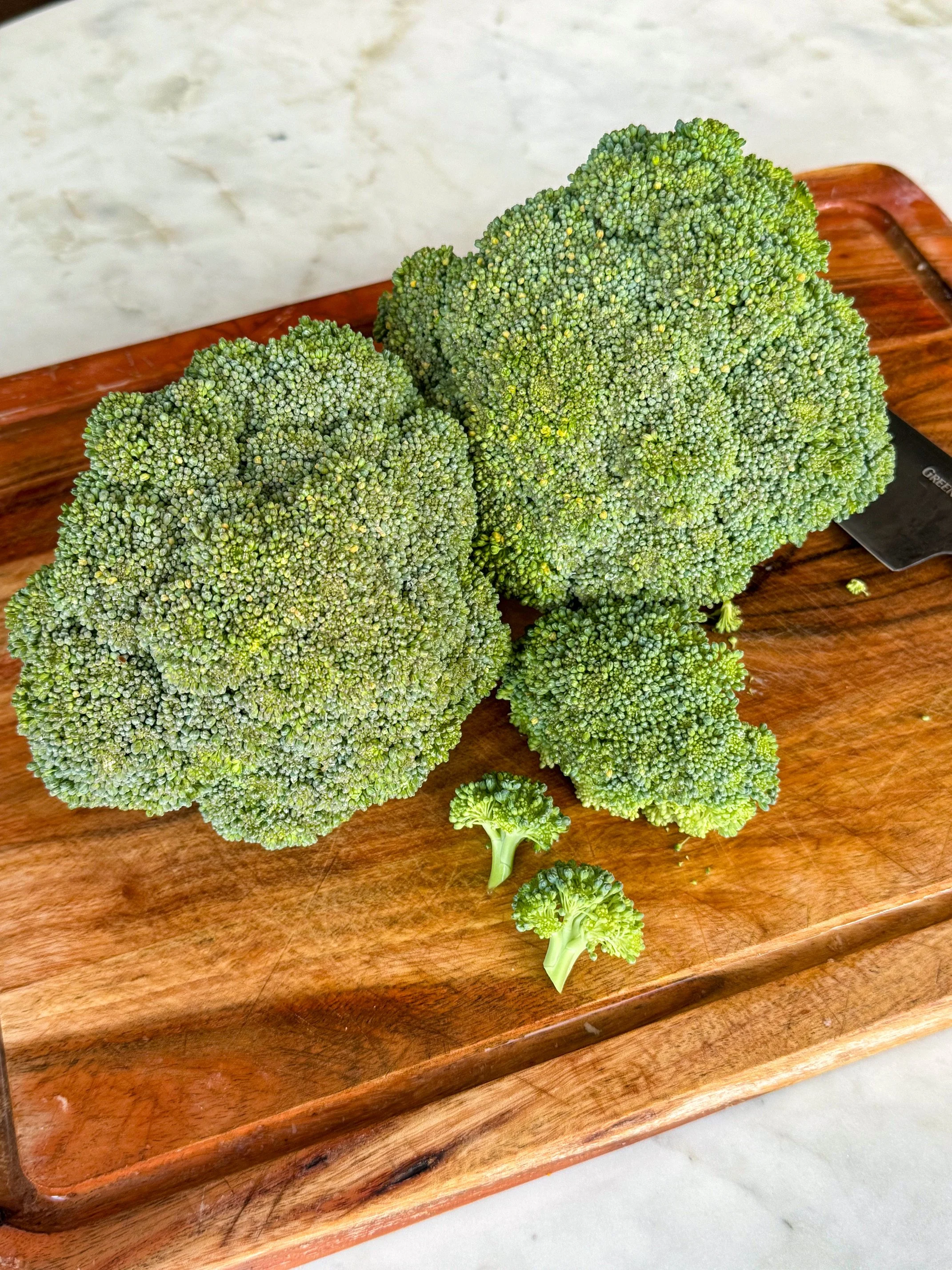 Fresh broccoli on a wooden cutting board.