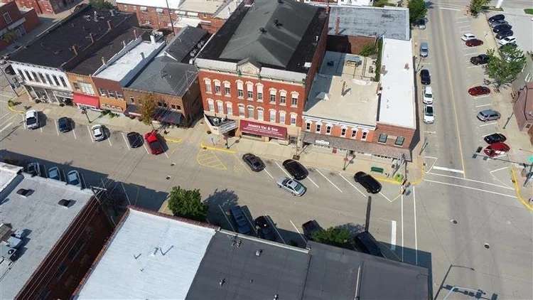 Aerial view of a small downtown street with parked cars and historic brick buildings.