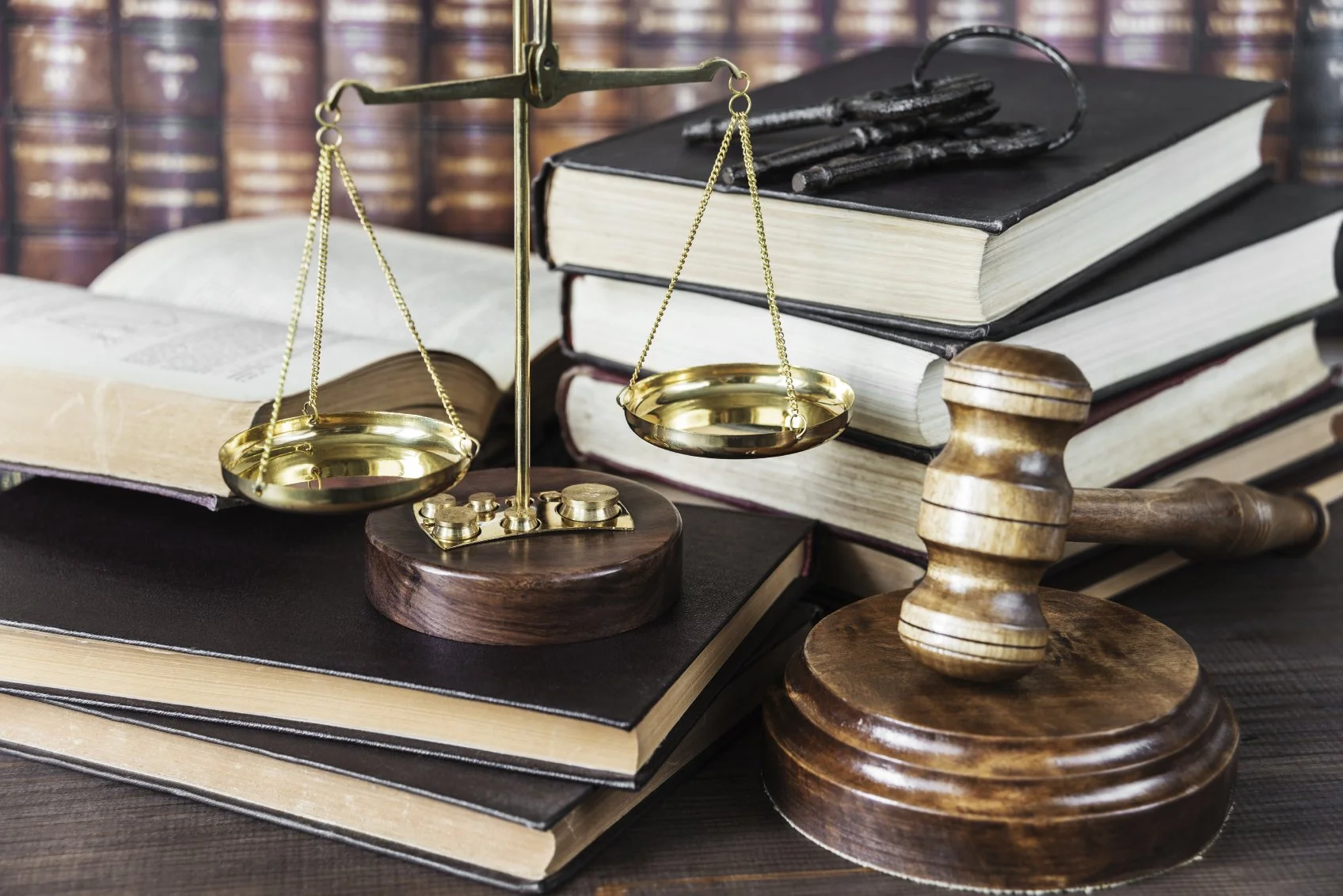 Legal tools including a gavel, balance scales, and law books on a wooden desk