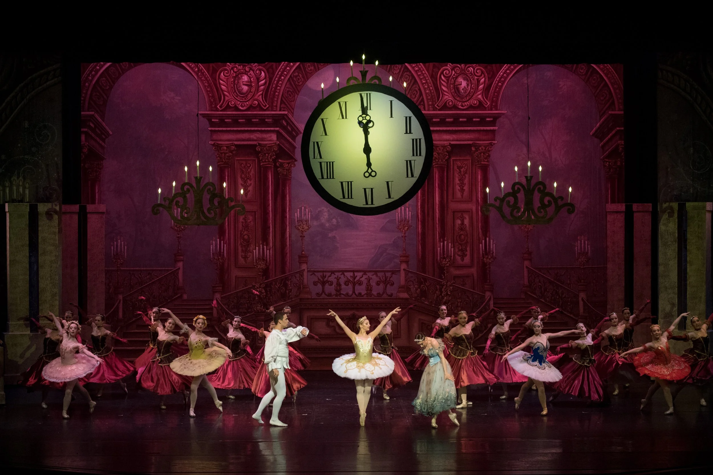 Ballet dancers performing on stage with a large clock showing midnight in the background.