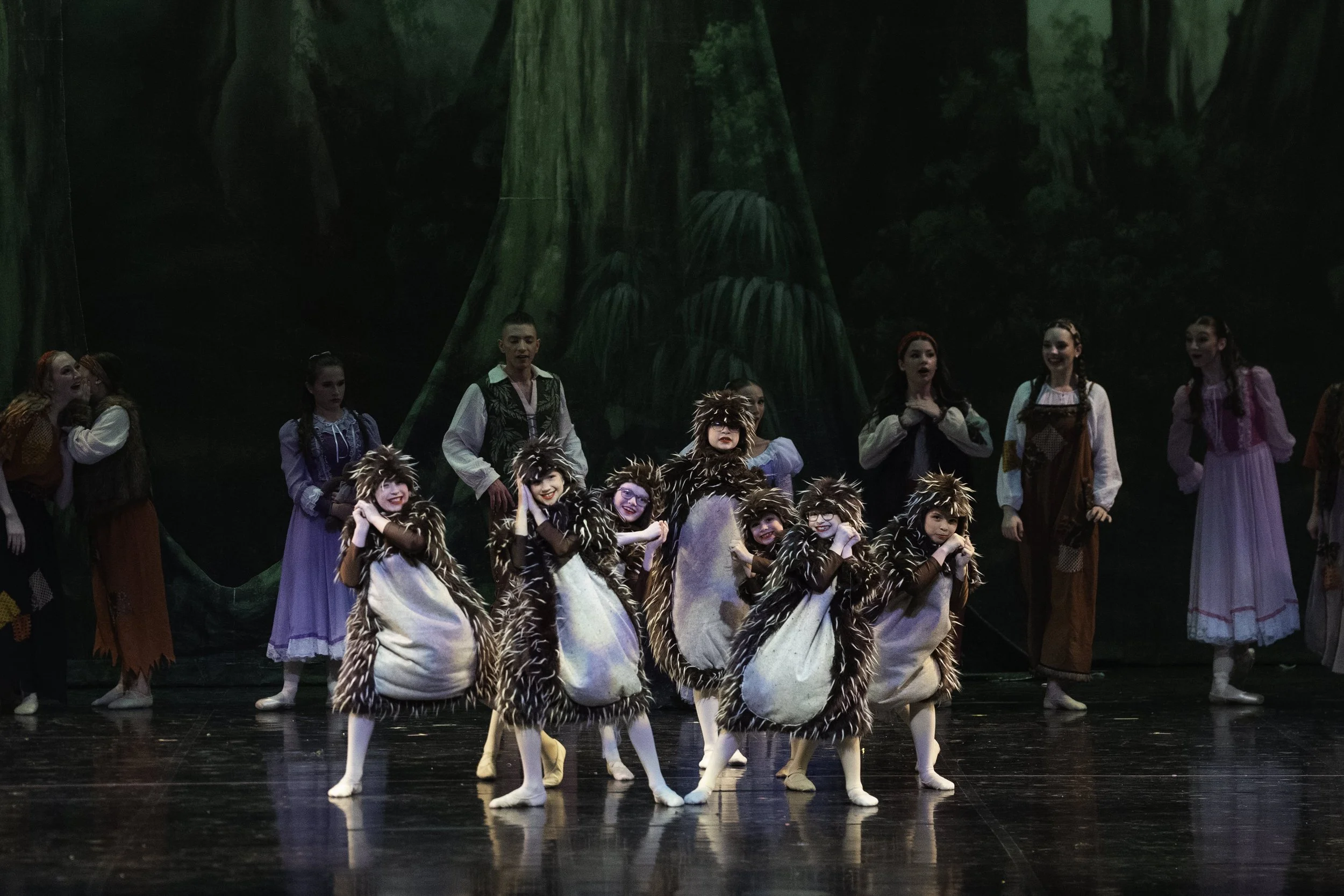 Children dressed as mice performing in a ballet on stage with a forest backdrop.