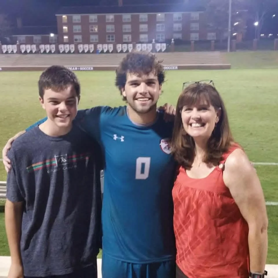 Coach Jake with family on the field after a collegiate win over top‑25 Furman.