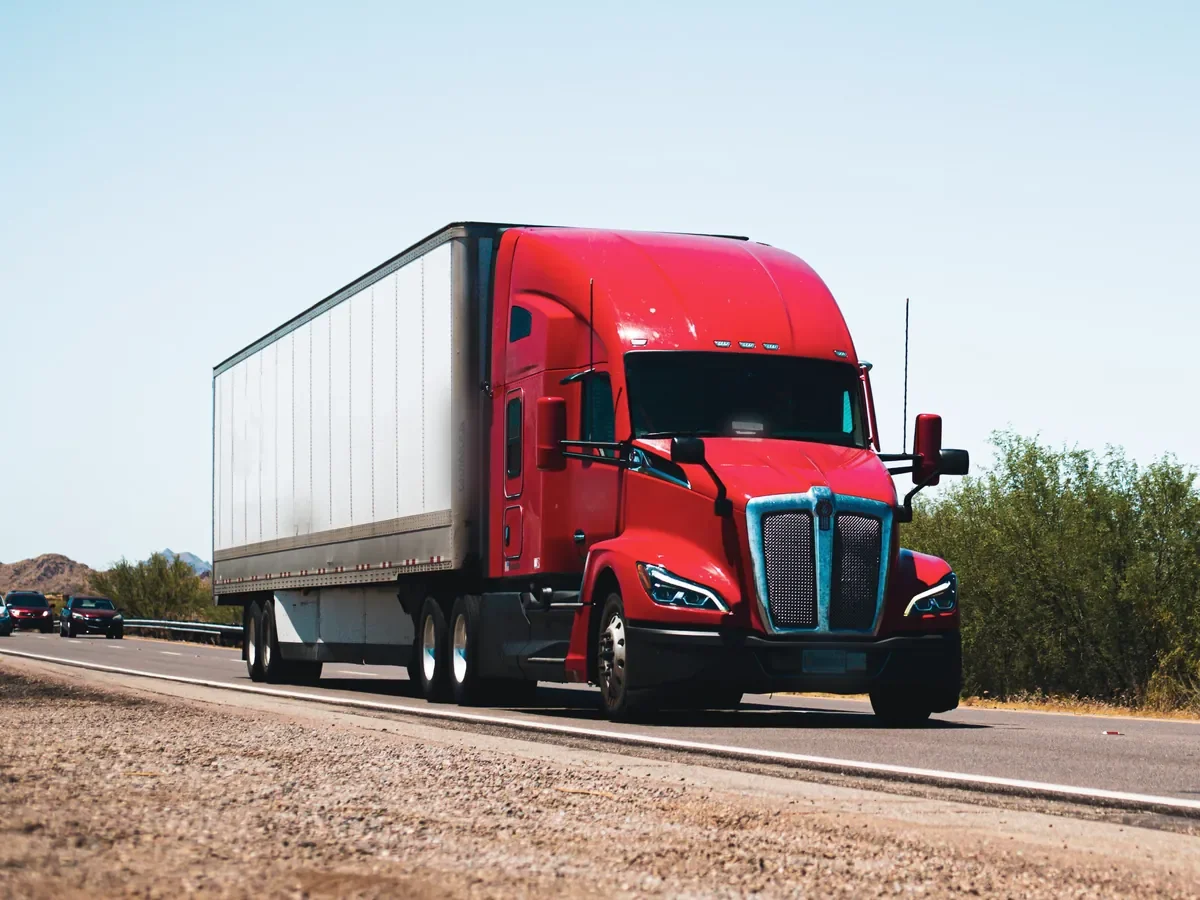 Red semi-truck pulling a white trailer on an open highway