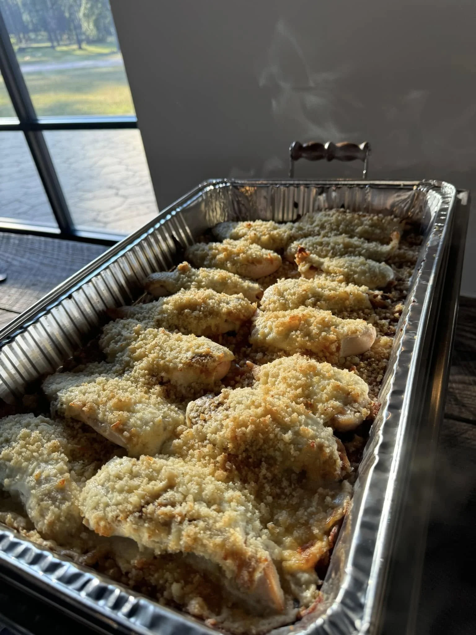Baked chicken topped with grated cheese in a foil tray