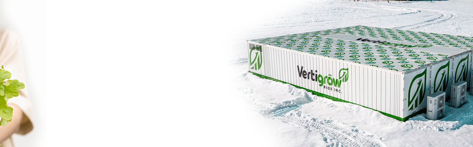 Large white storage container with green logo and lettering 'Vertigrow BIOS Inc.', situated on snow-covered ground, with two air conditioning units at the corner of the container in a snowy landscape.