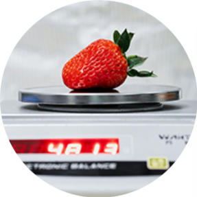 A large strawberry placed on a digital kitchen scale displaying 48.2 grams.