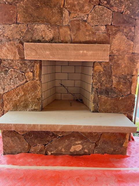 Empty brick fireplace with a stone outer surround and a tiled interior