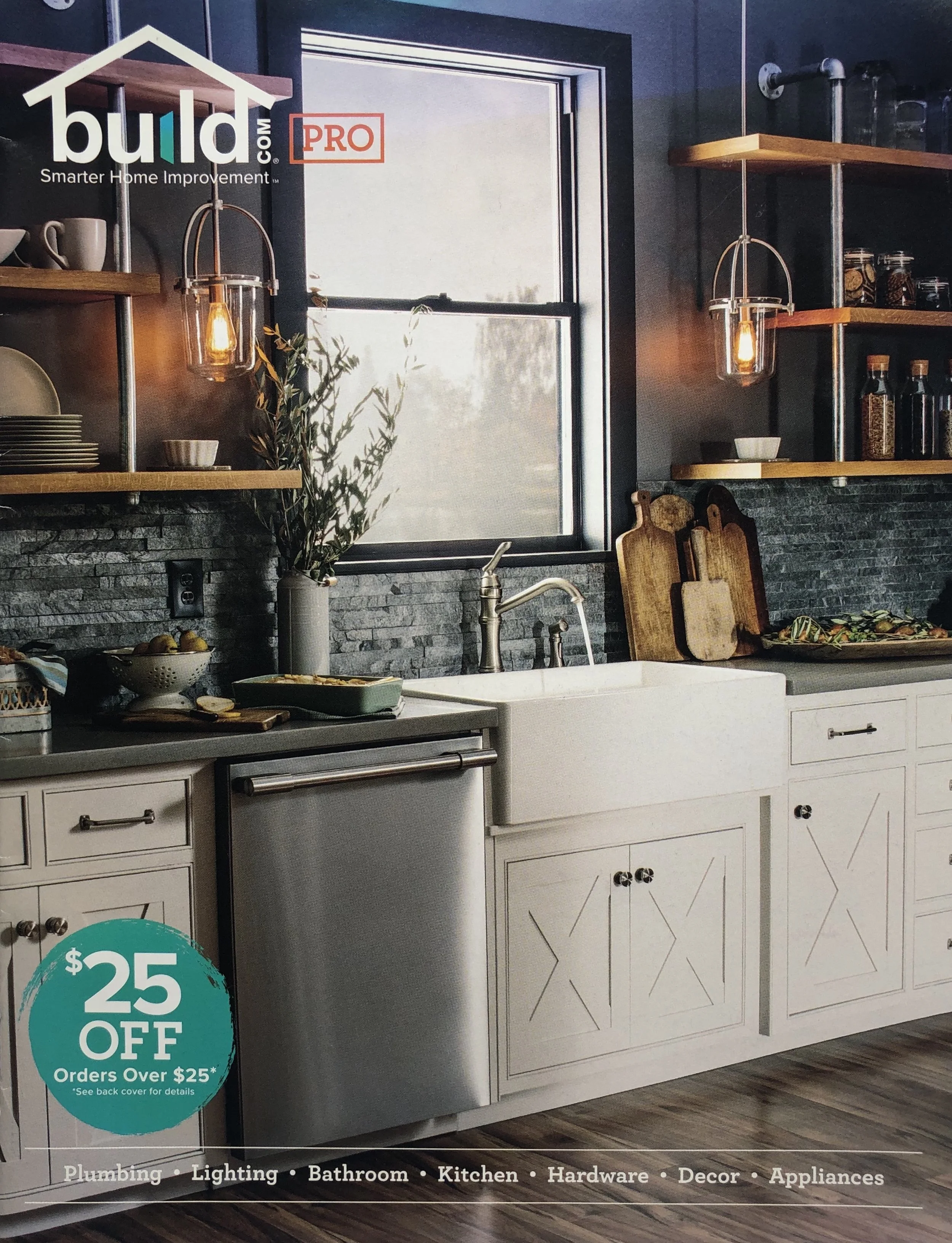 Interior of a kitchen display in a home improvement store with a white farmhouse sink, wooden open shelves holding dishes and jars, a black tiled backsplash, a window, and various kitchen accessories. A blue and green sign indicates a $25 off discoun