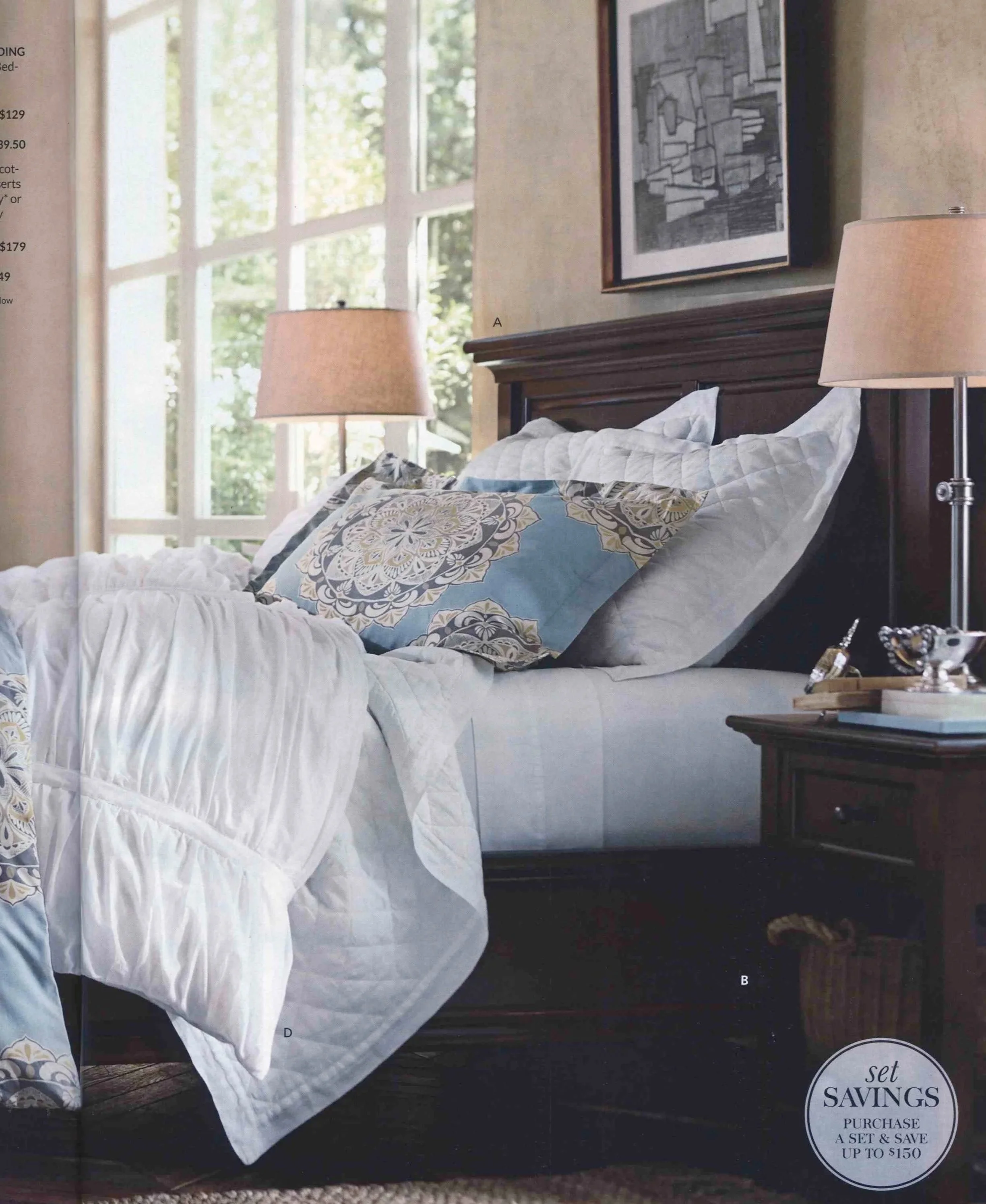 Interior Styling of a  bedroom with large windows, a wooden headboard, and a bed with white and patterned bedding. There are two bedside lamps and a framed piece of art on the wall. A tray with jewelry is on a nearby table.