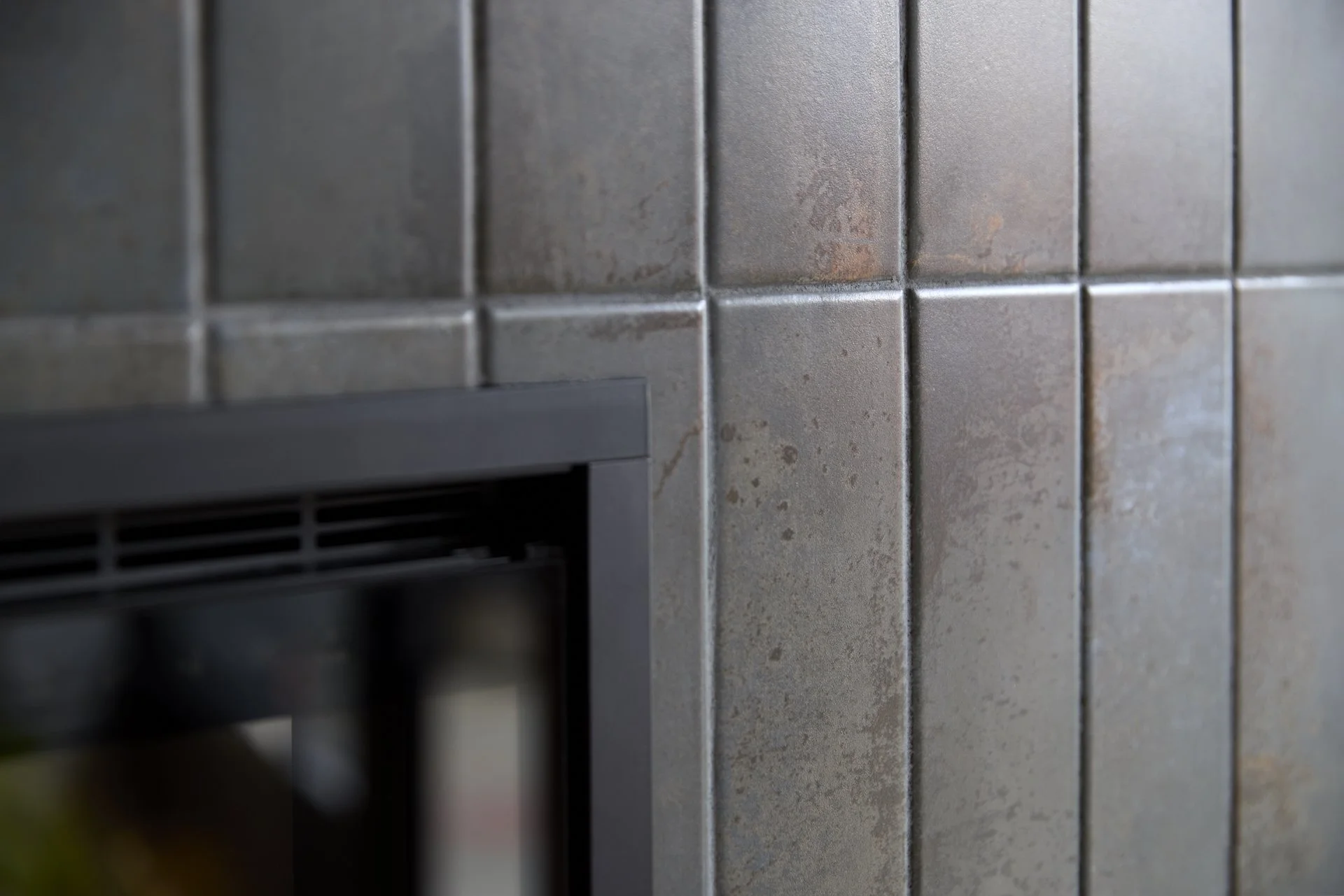 Close-up of tiled wall with metal vent in a kitchen or industrial setting.