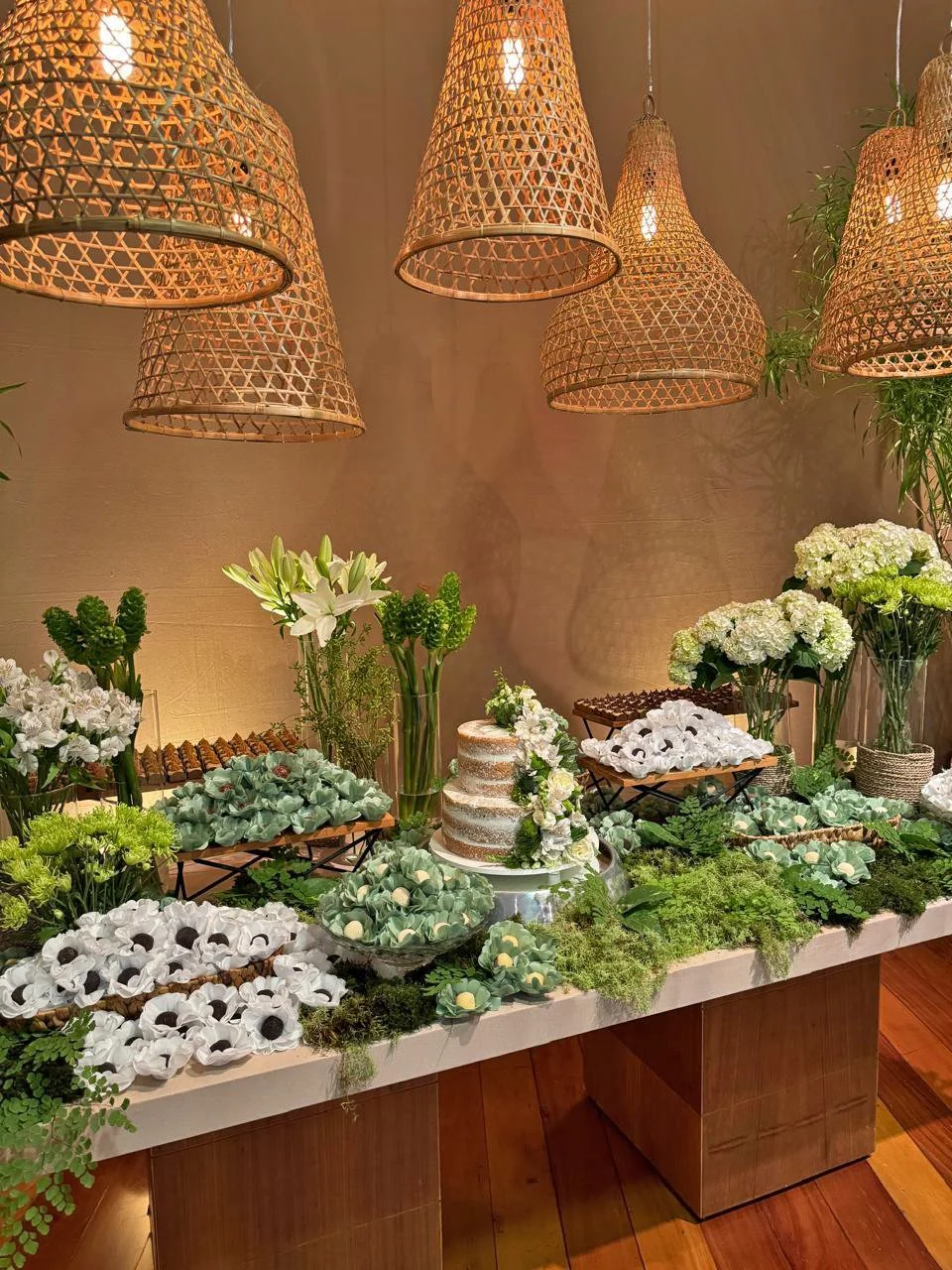 Festa de casamento clássico em bege verde e branco no salão lounge mesa de bolo e doces com luminárias rattan