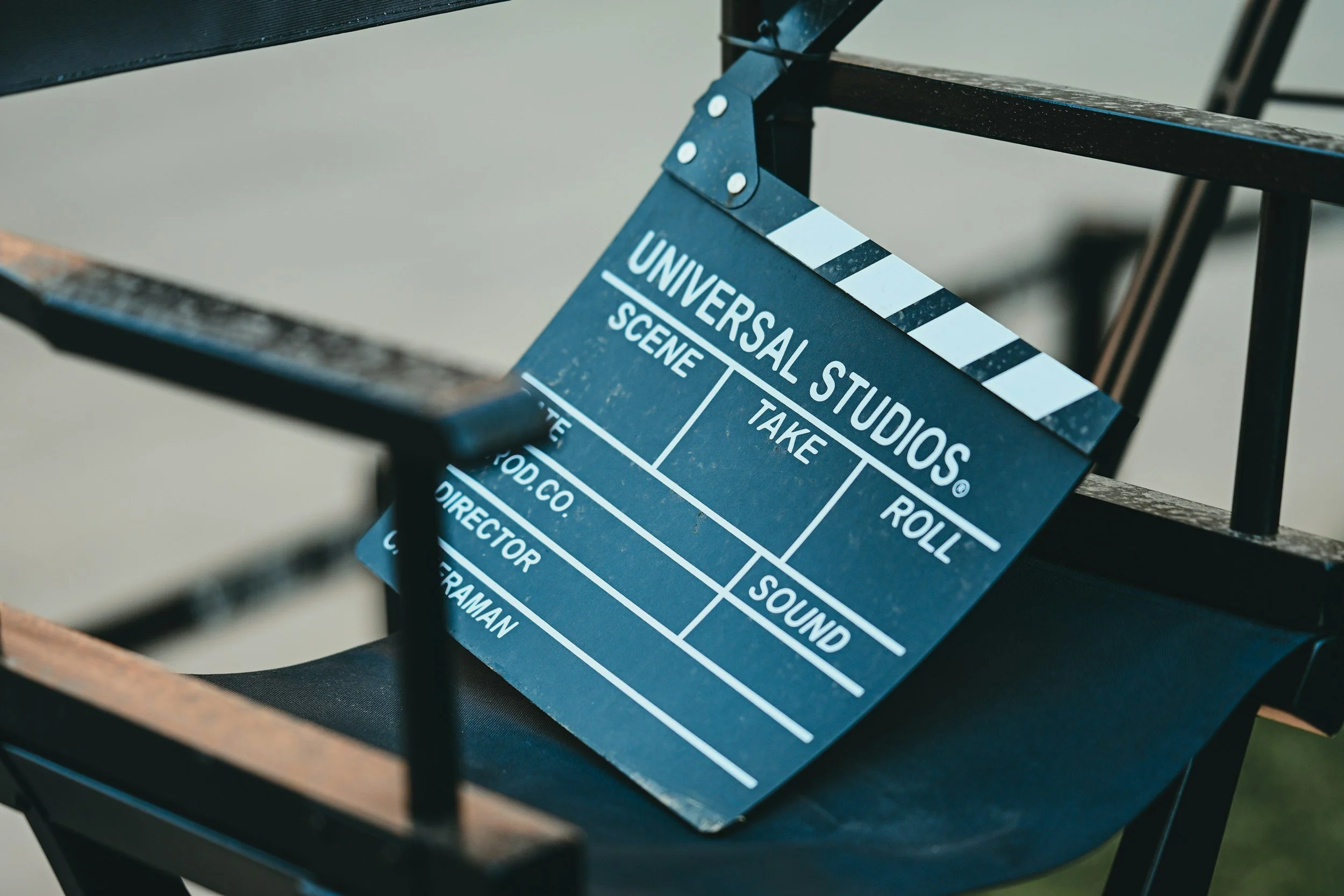 Close-up of a black and white film clapperboard resting on a dark wooden surface with a black metal frame structure in the background.