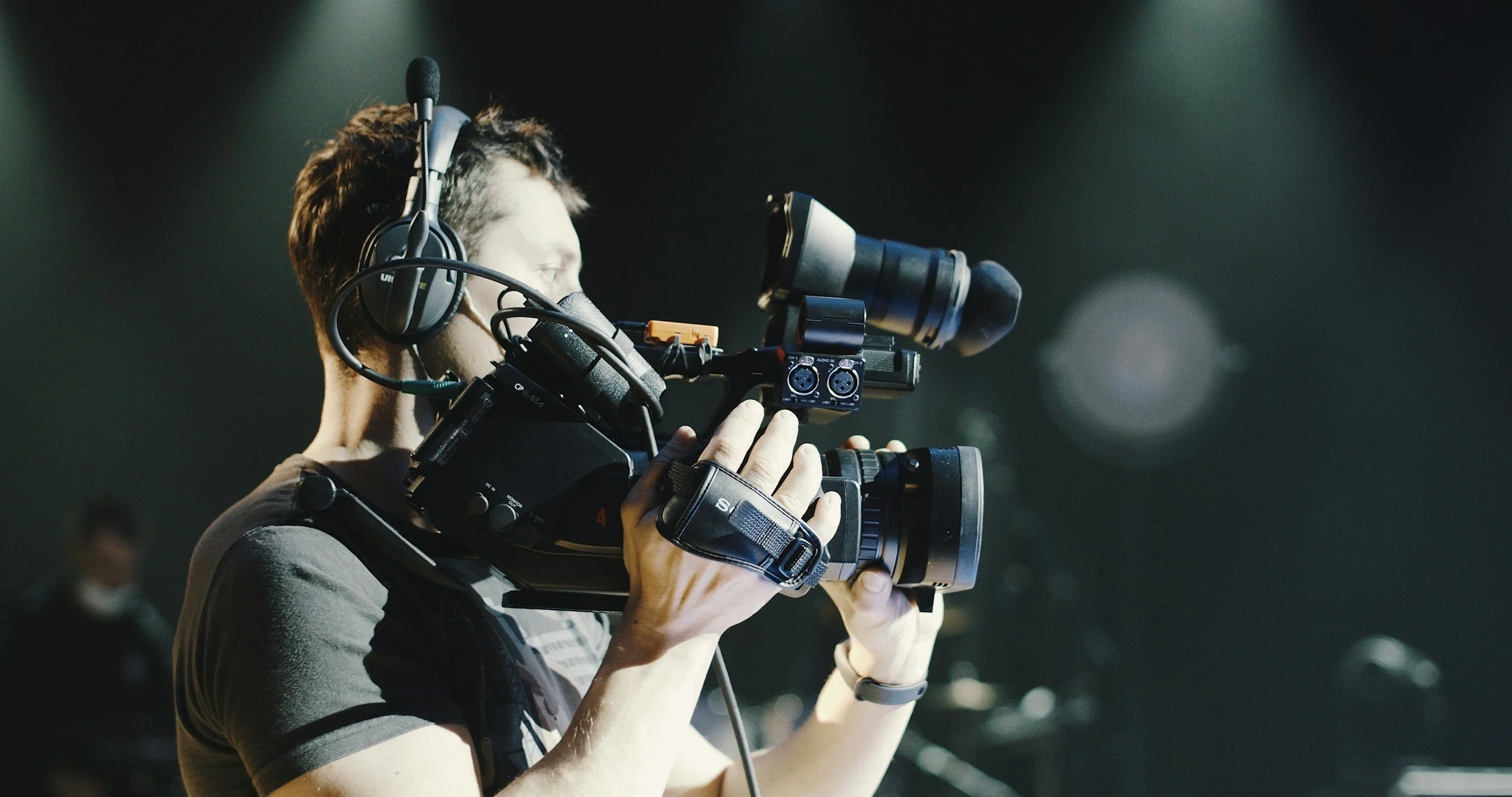 Person operating a professional video camera with headphones, focusing on filming.