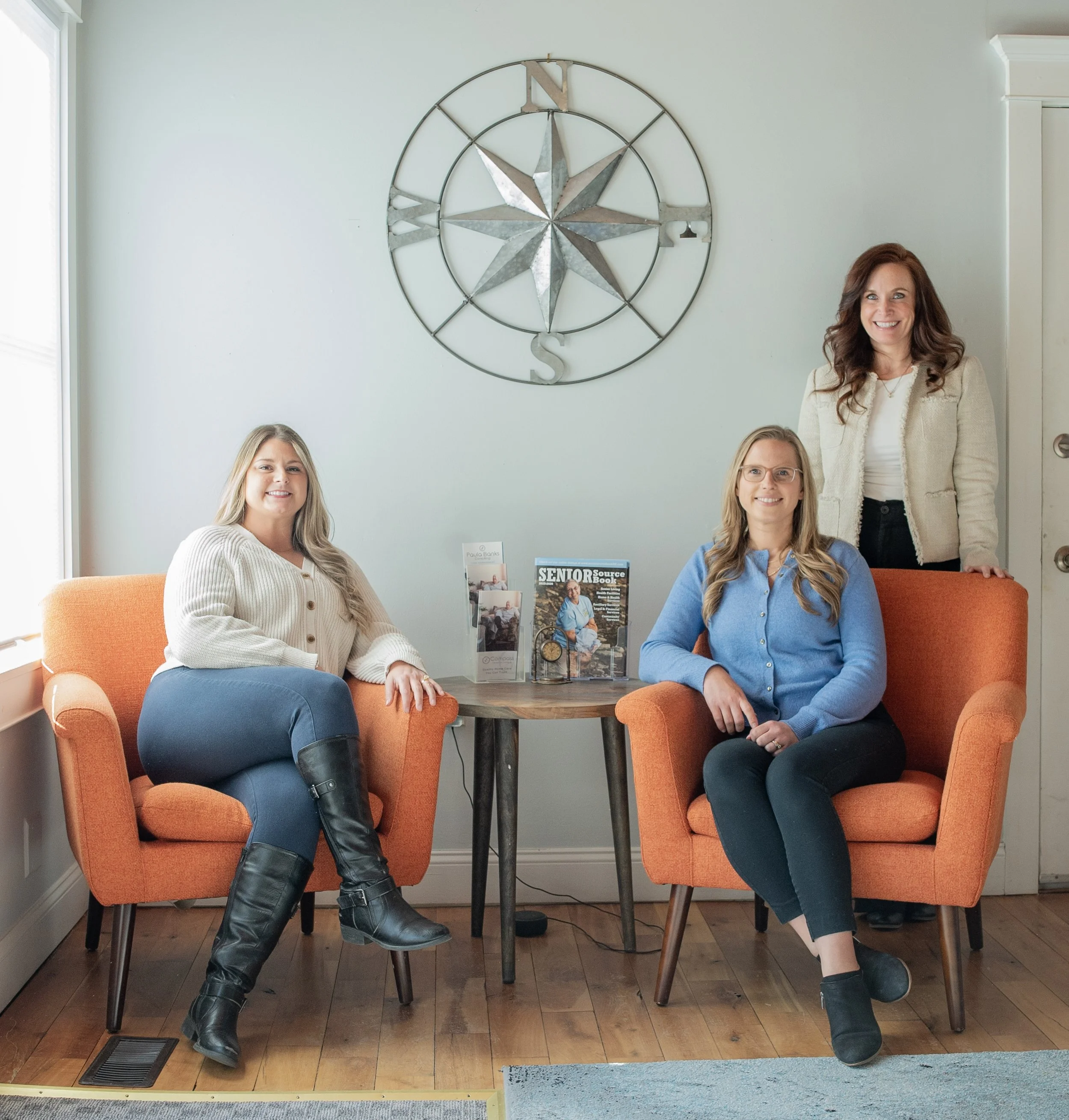 Compass Concierge and Companions Team Photo with Compass on wall