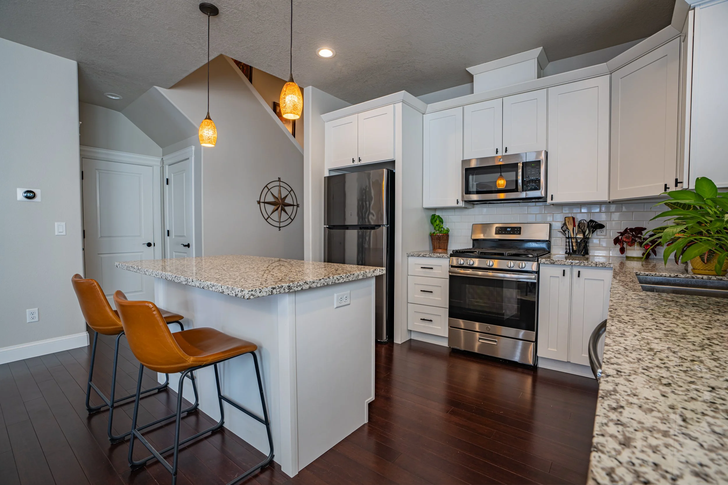 Open-concept kitchen with granite island, stainless steel appliances, white shaker cabinets, and hardwood floors in a Salem, Oregon home